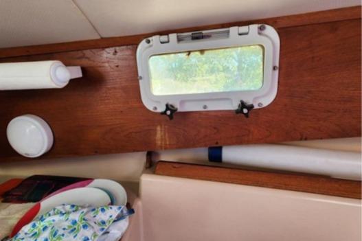 Interior of 1985 Wasque Down East Cruiser with wooden paneling and porthole window.