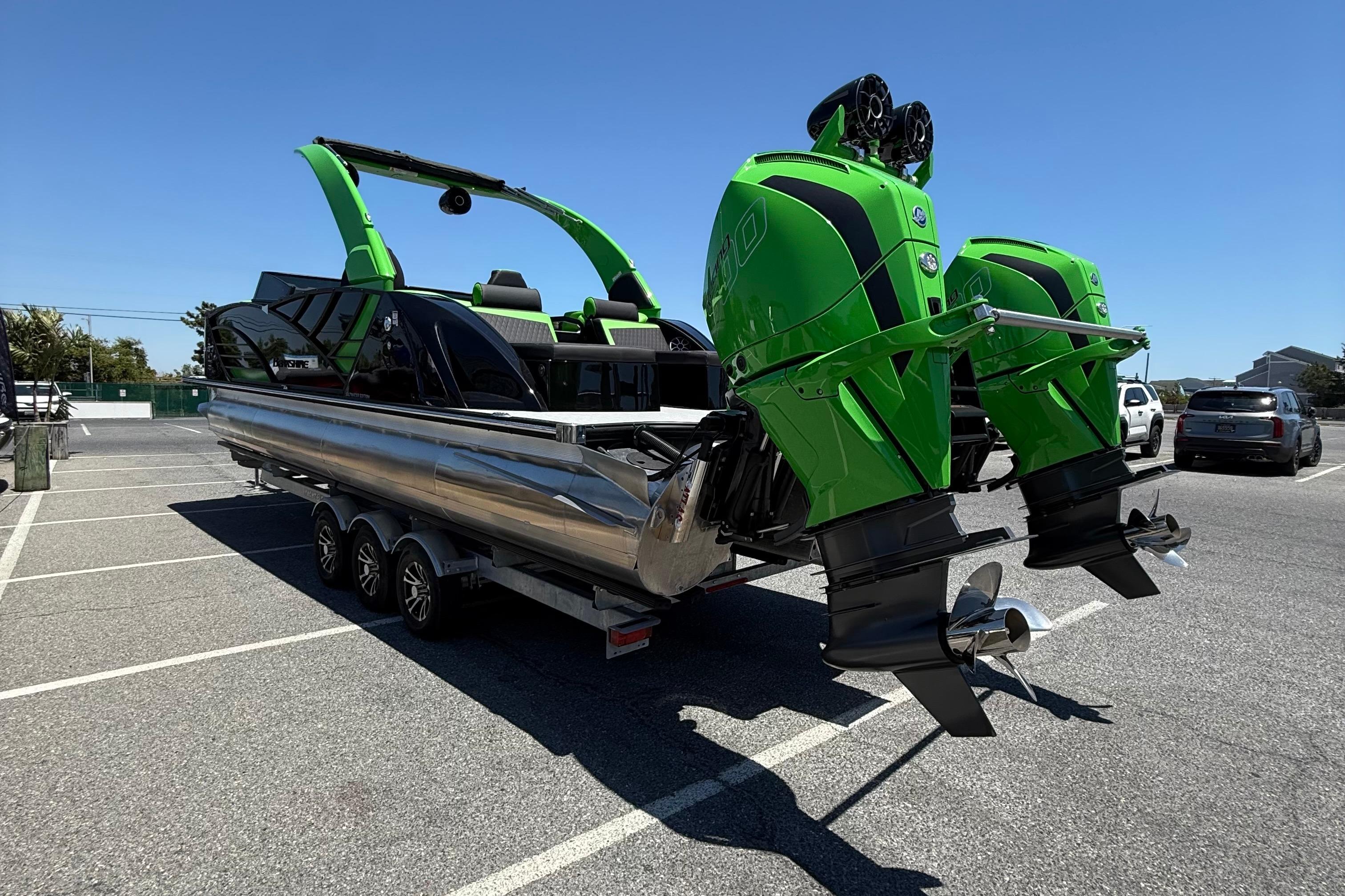 2026 Berkshire Sport SLX9 DC pontoon boat with dual green outboard motors in a parking lot.