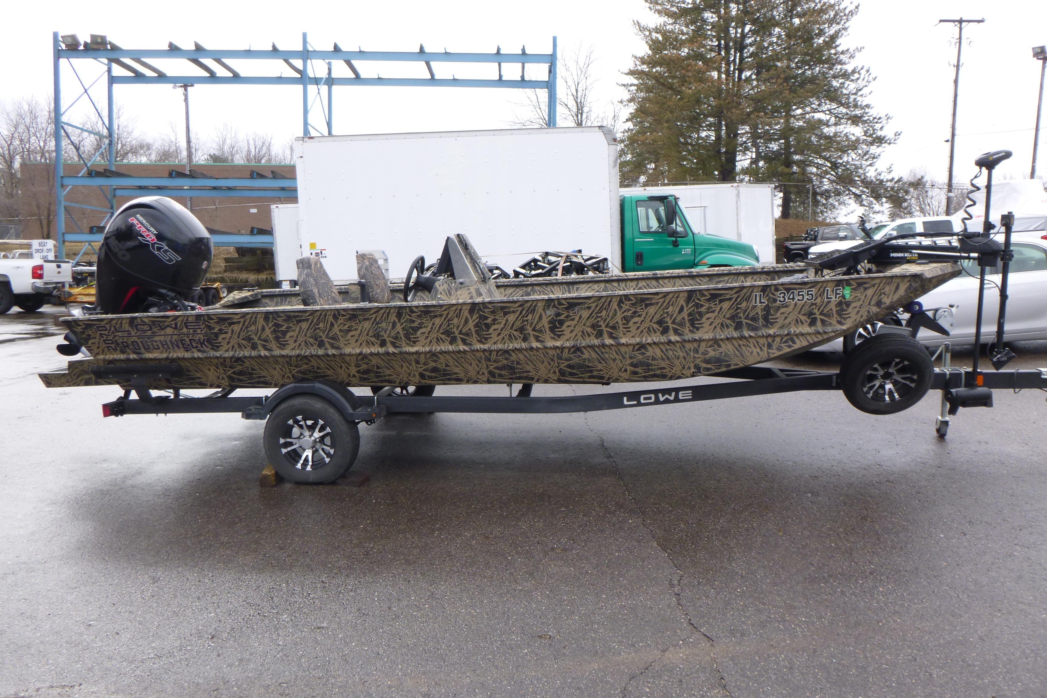 2024 Lowe Roughneck 2070 boat on trailer, camo design, parked outdoors.