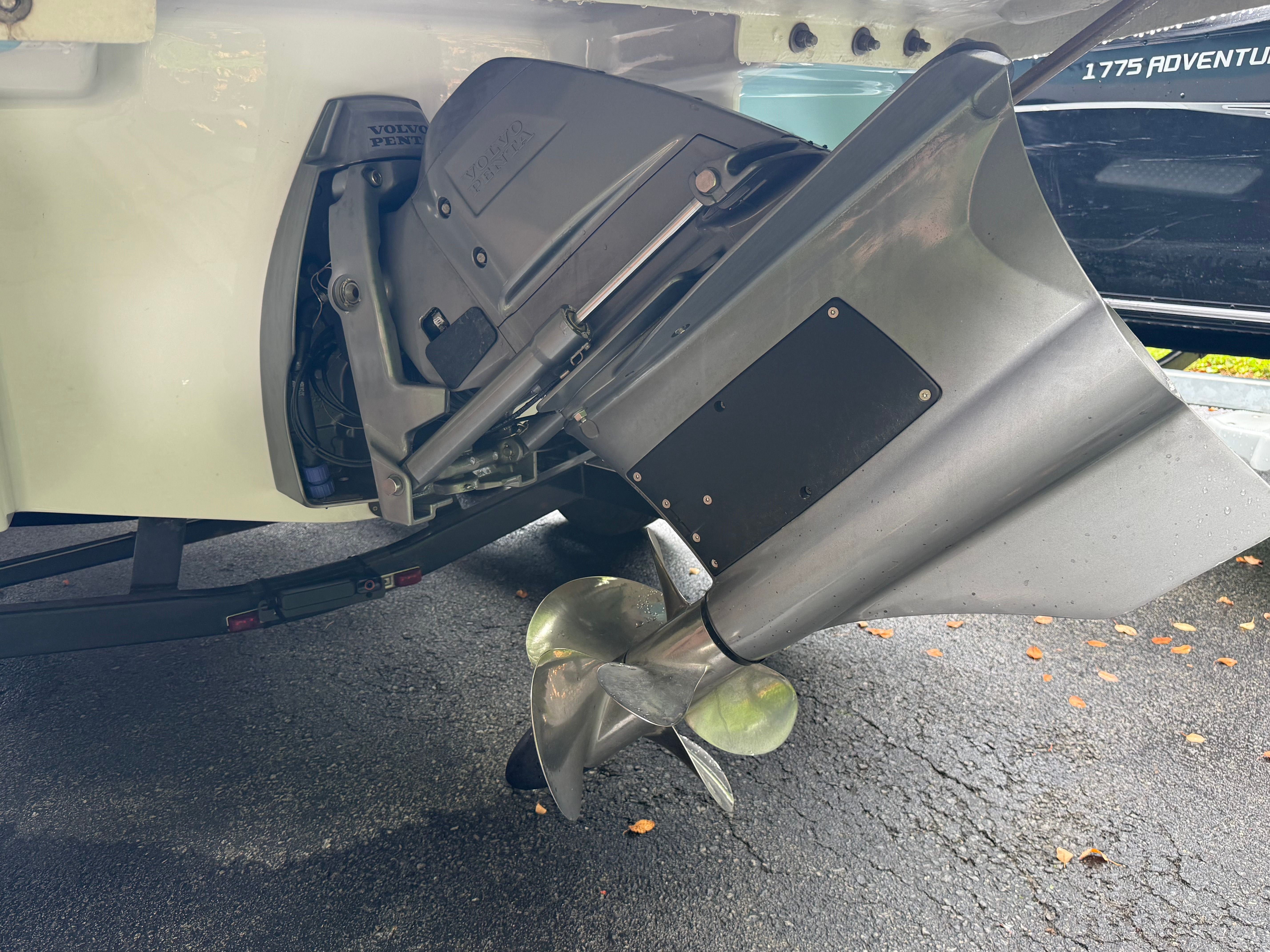 Close-up of a boat engine with propeller, mounted on a trailer, on a paved surface.