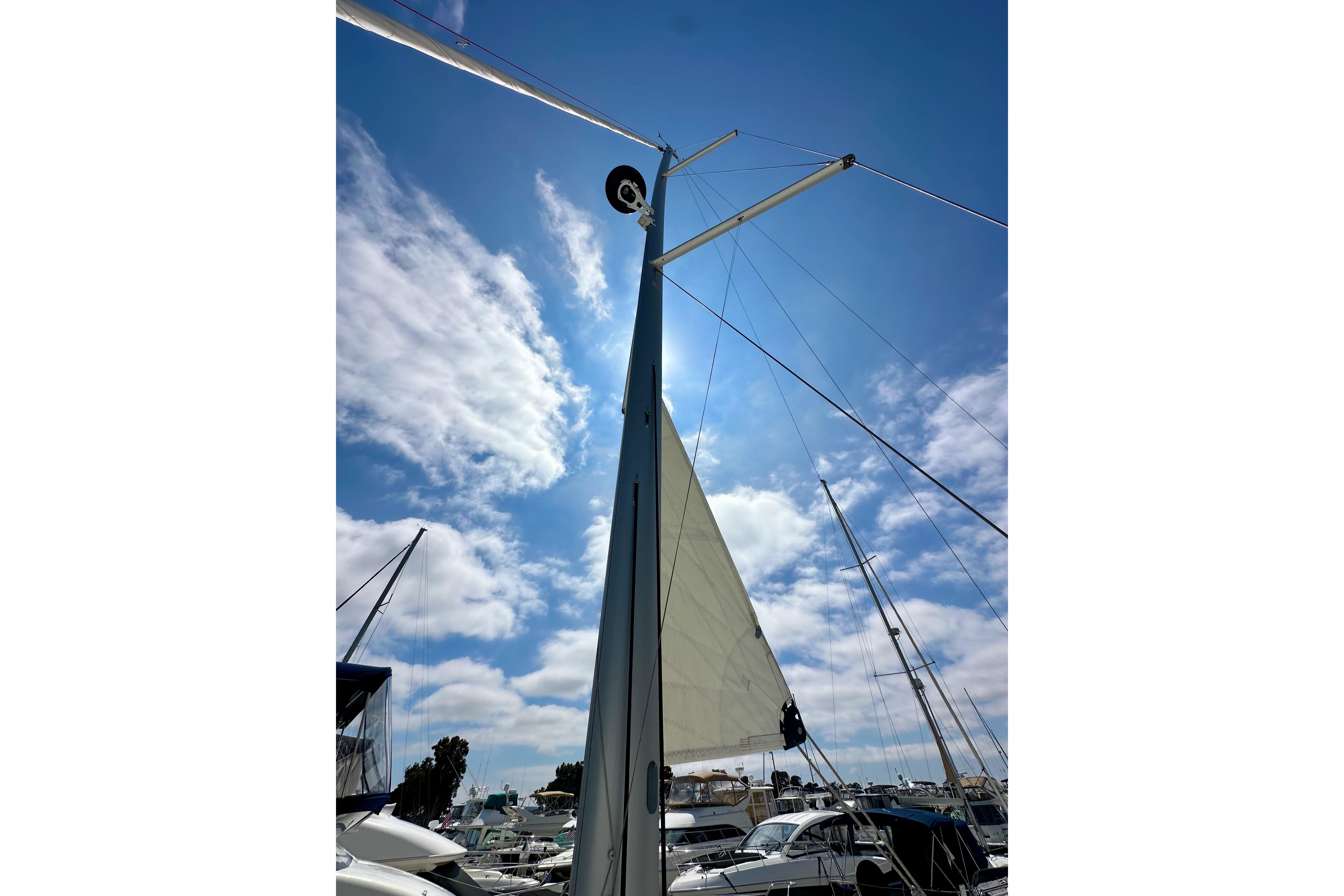 Sailboat mast and sail of 2024 Jeanneau Sun Odyssey 410 against a blue sky.