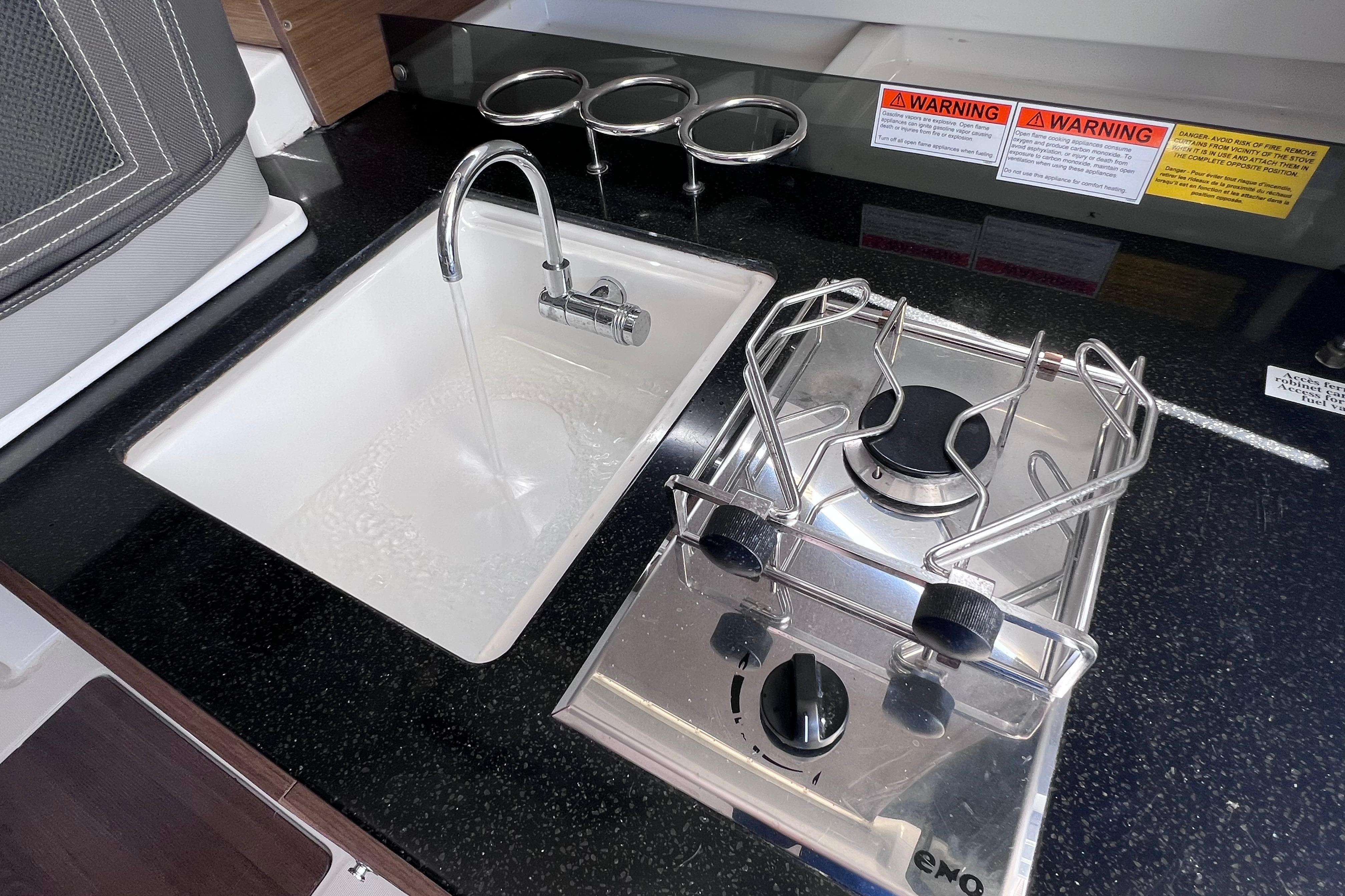 Compact kitchen area in 2021 Jeanneau NC Weekender 795 Series 2 with sink and stove.