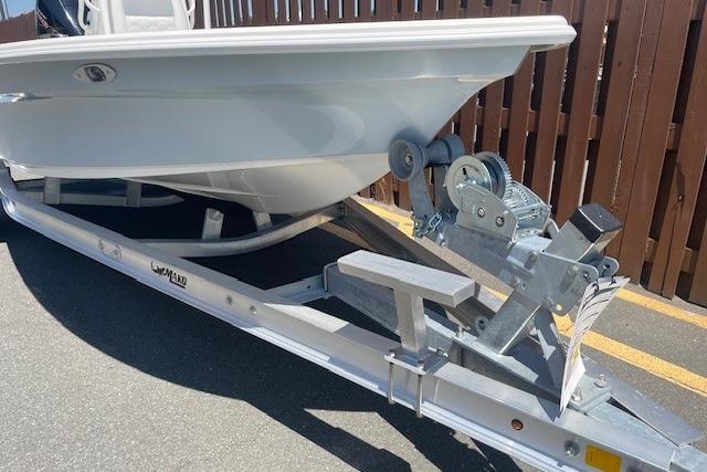 2026 Mako 18 Pro Skiff boat on trailer, parked near wooden fence.