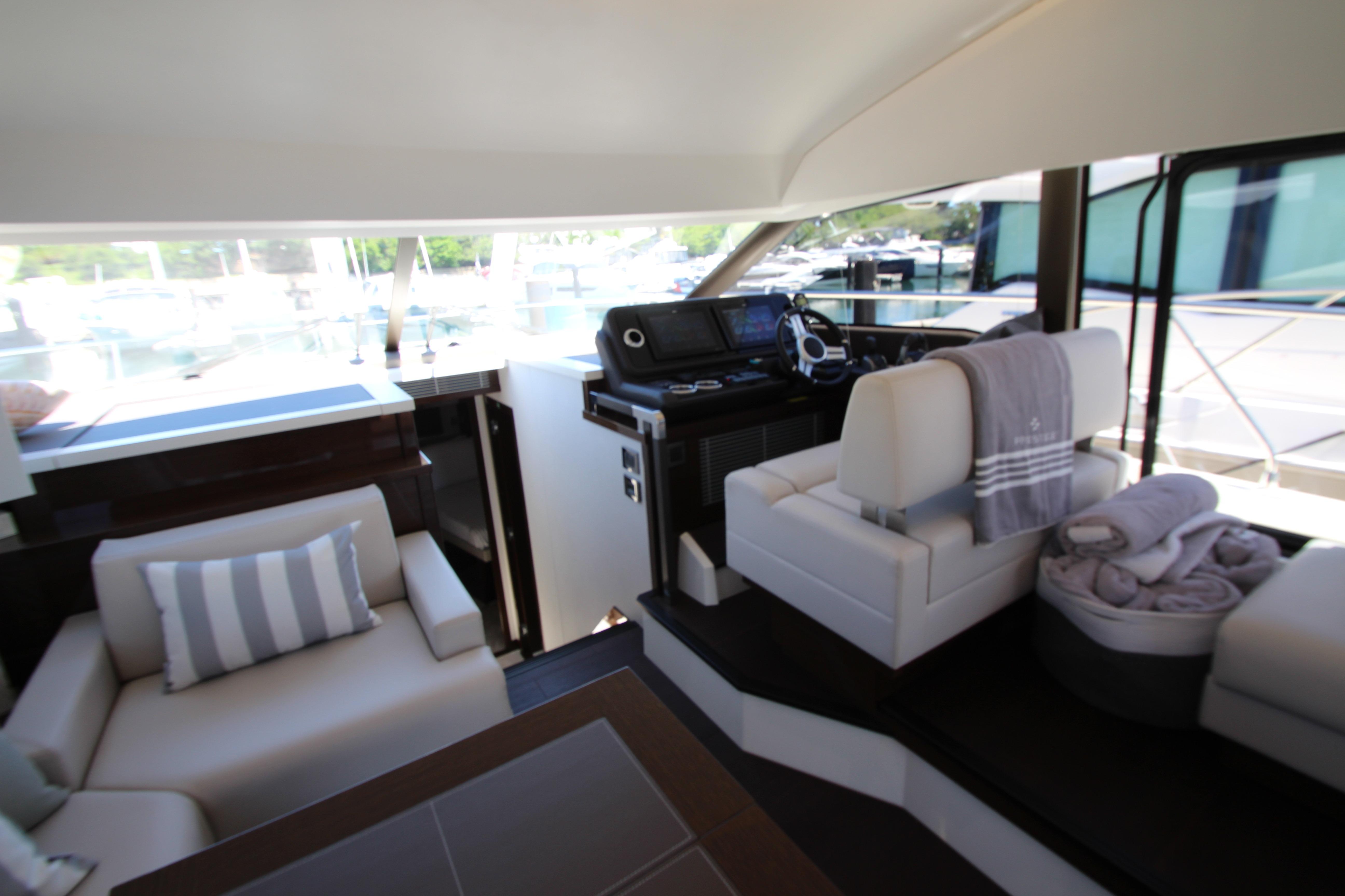 Luxurious interior of 2022 Prestige 520 yacht with modern seating and helm station.