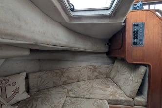Starboard side view of V-berth with cushioned seating and control panel.