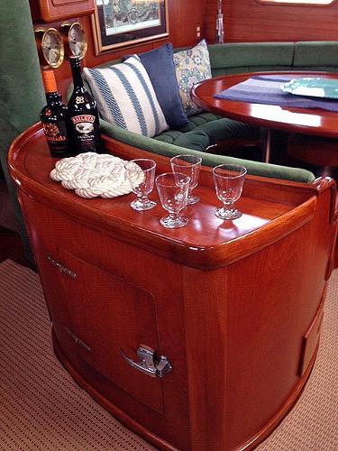 Interior view of a yacht with wooden furniture, a table, and glasses on a counter.
