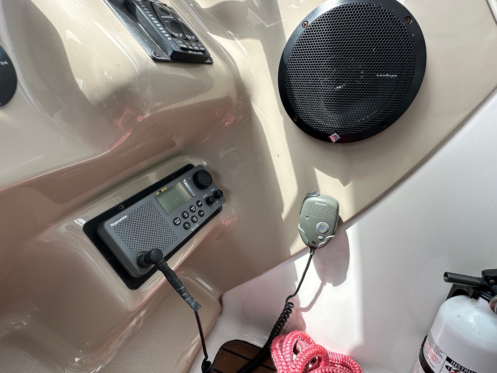 Close-up of a boat dashboard with speaker, radio, and fire extinguisher.