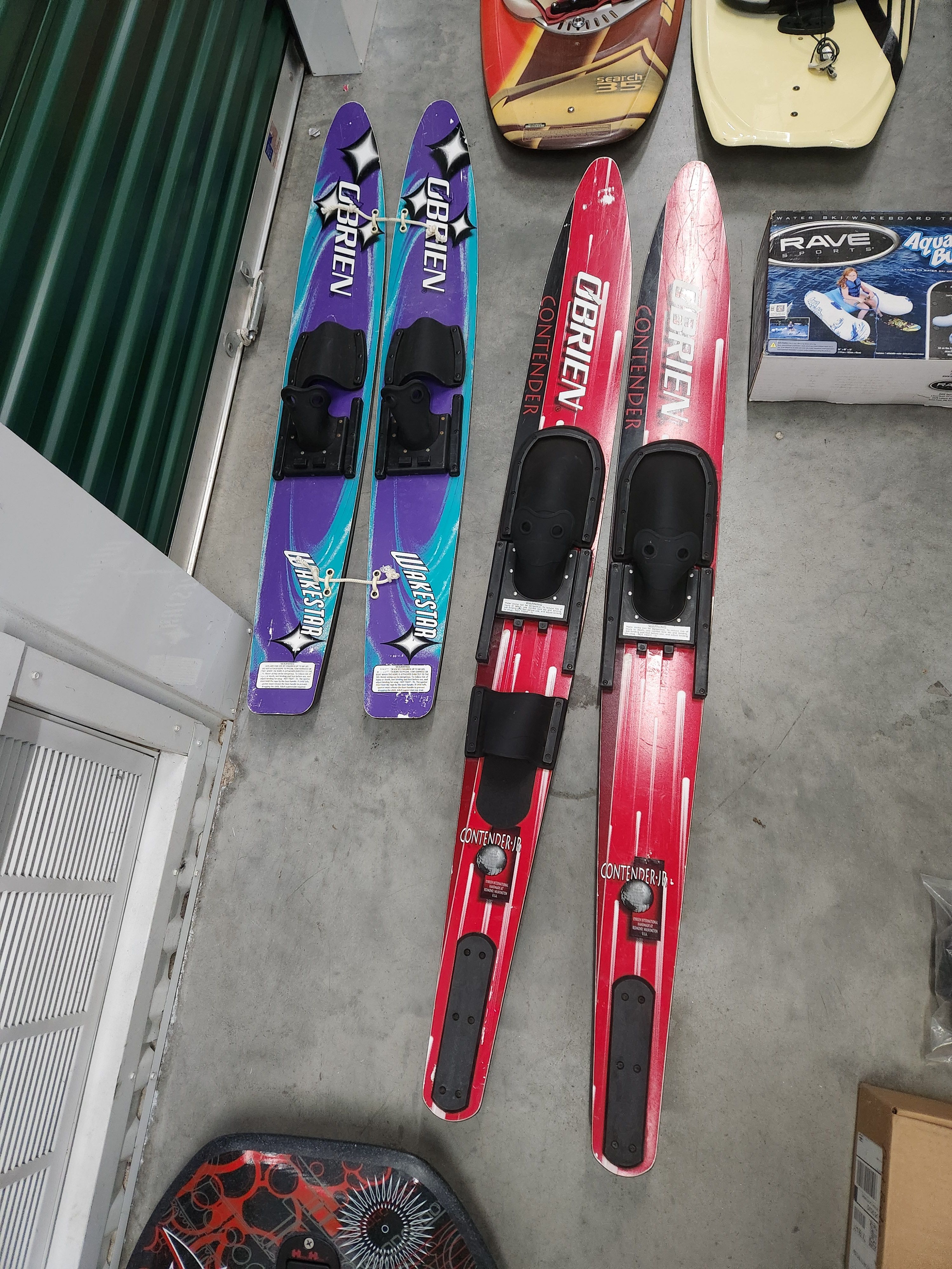 Two pairs of O'Brien water skis on concrete floor.