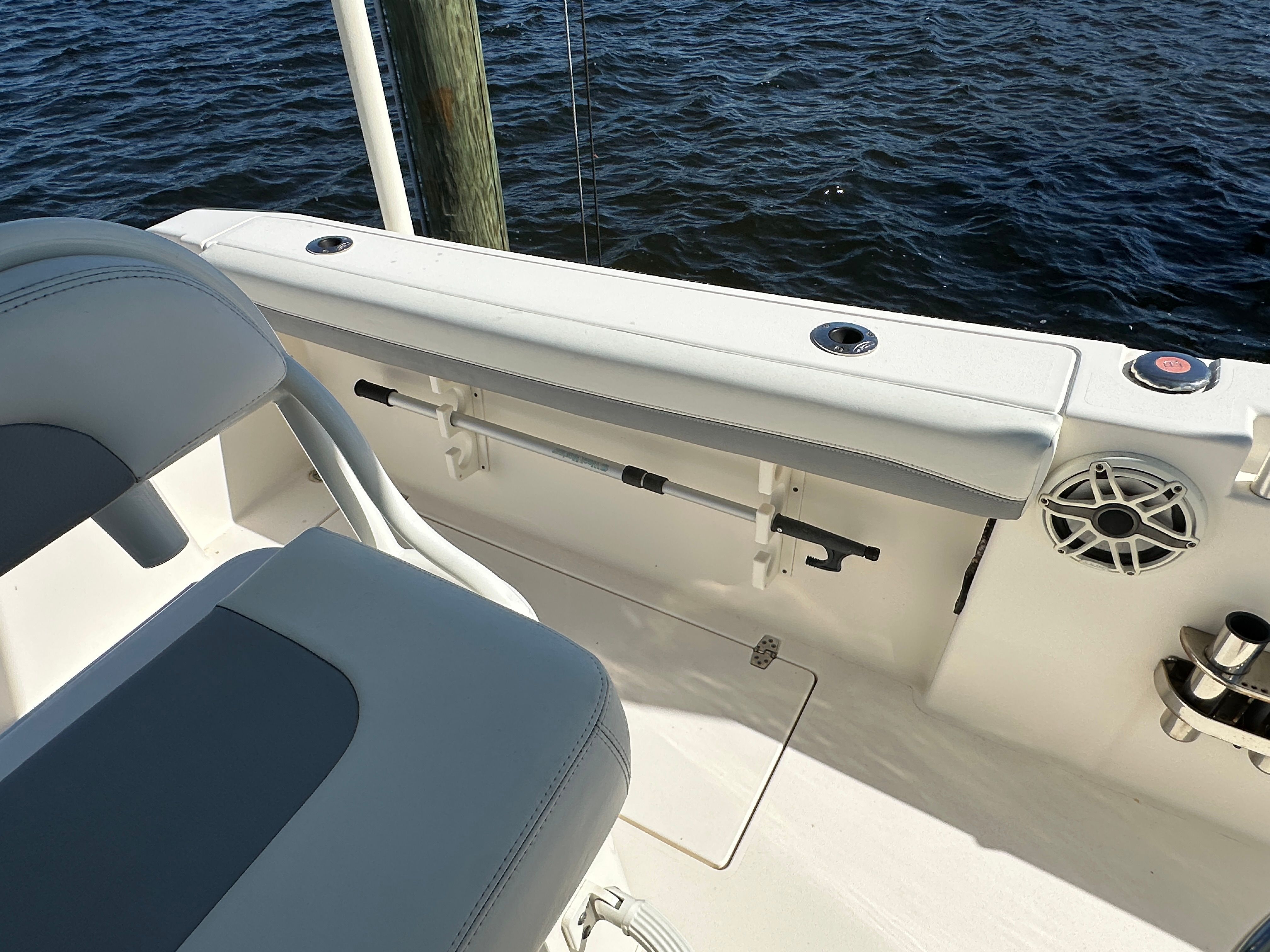 The image shows the cockpit of a 2022 Cobia 240 Center Console boat by the water.
