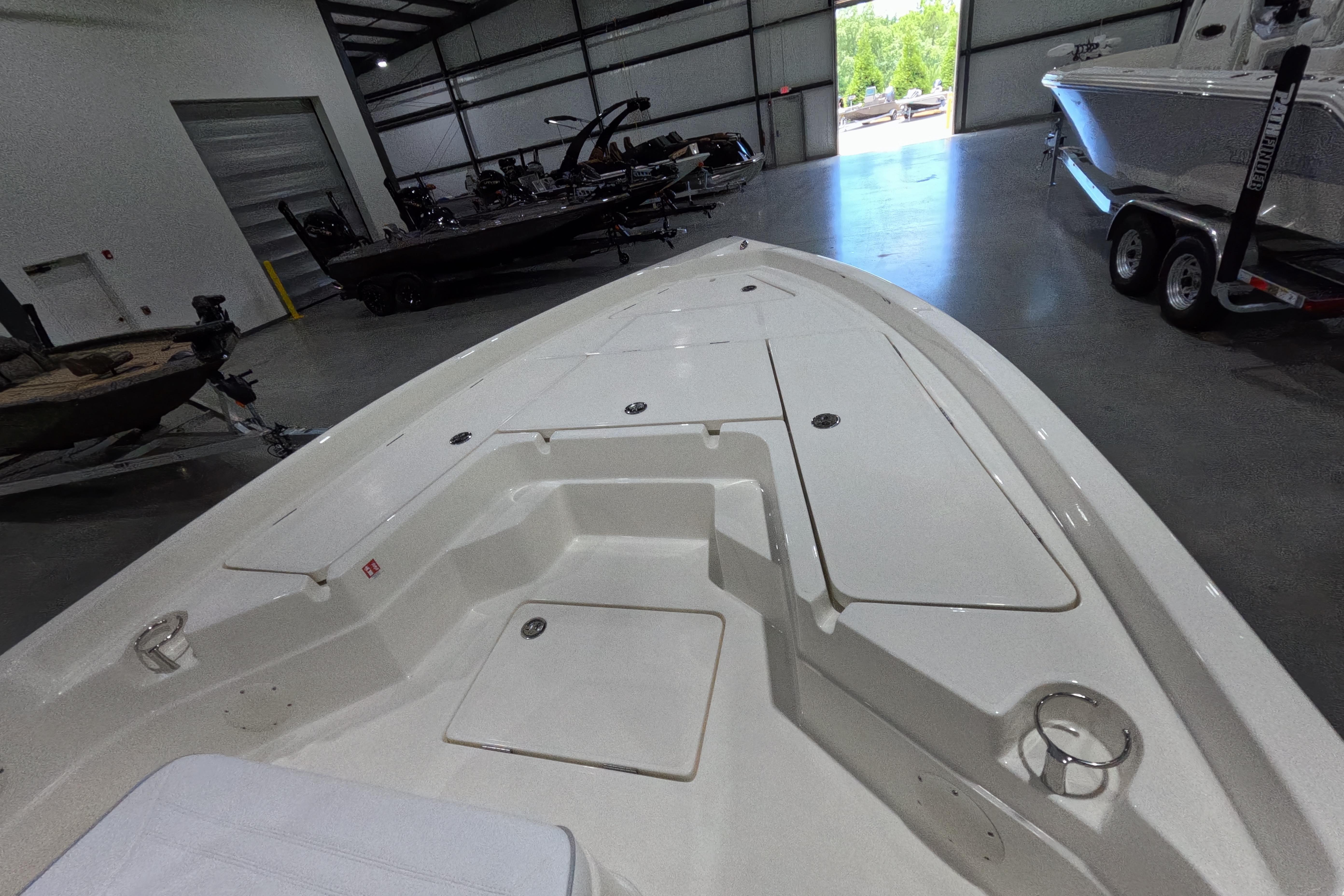 2026 Skeeter SX230 boat interior in showroom, showcasing spacious deck and storage compartments.