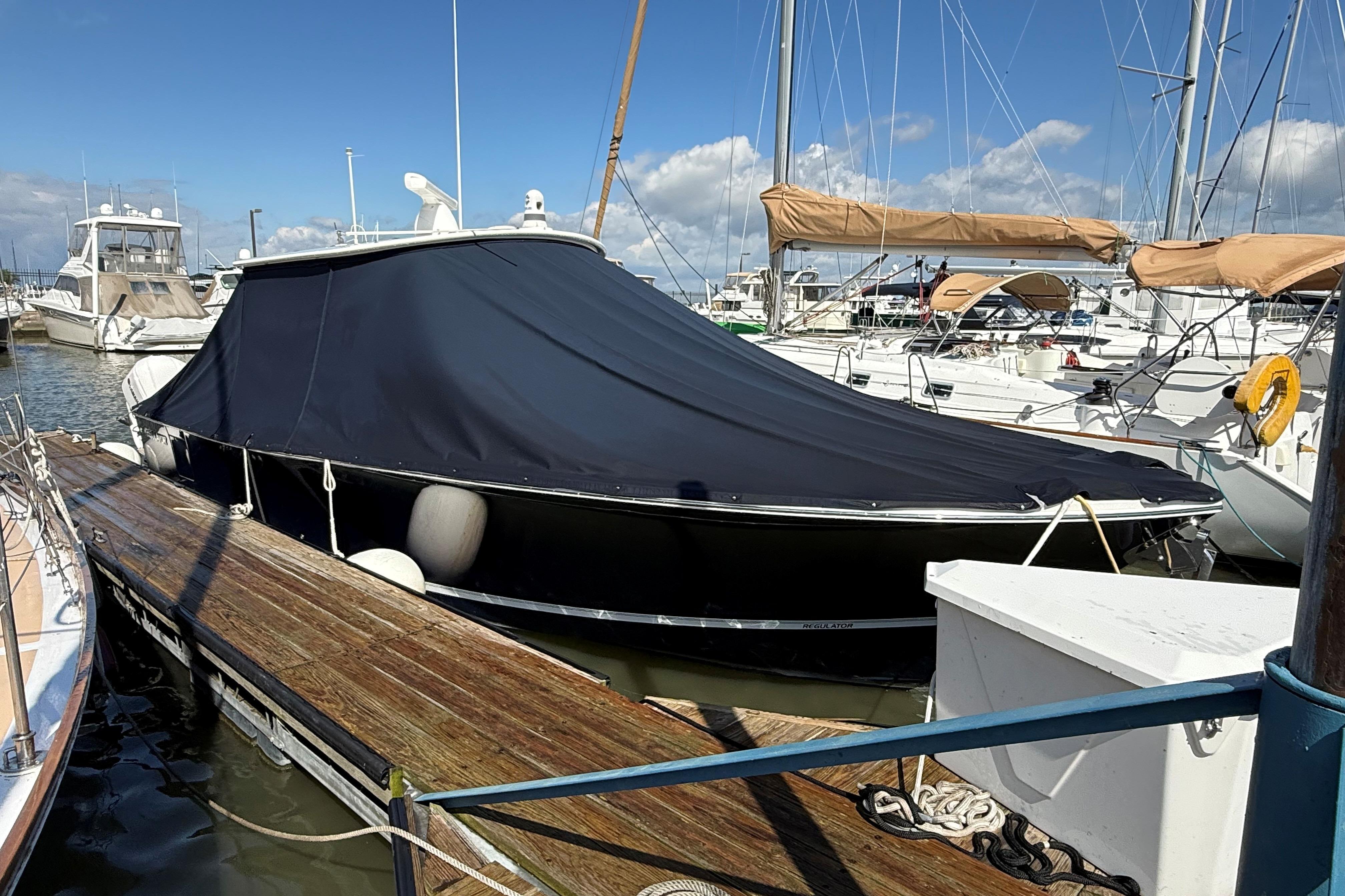2019 Regulator 34SS boat covered at marina dock under blue sky.