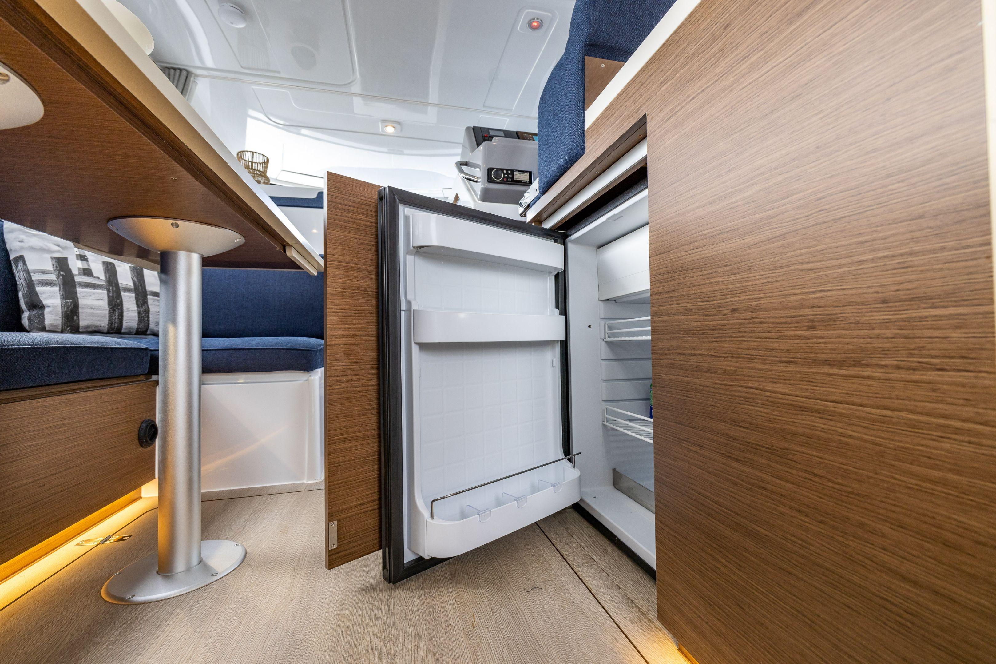 Interior of 2026 Delphia D11 Flybridge yacht with open fridge and modern wood finish.