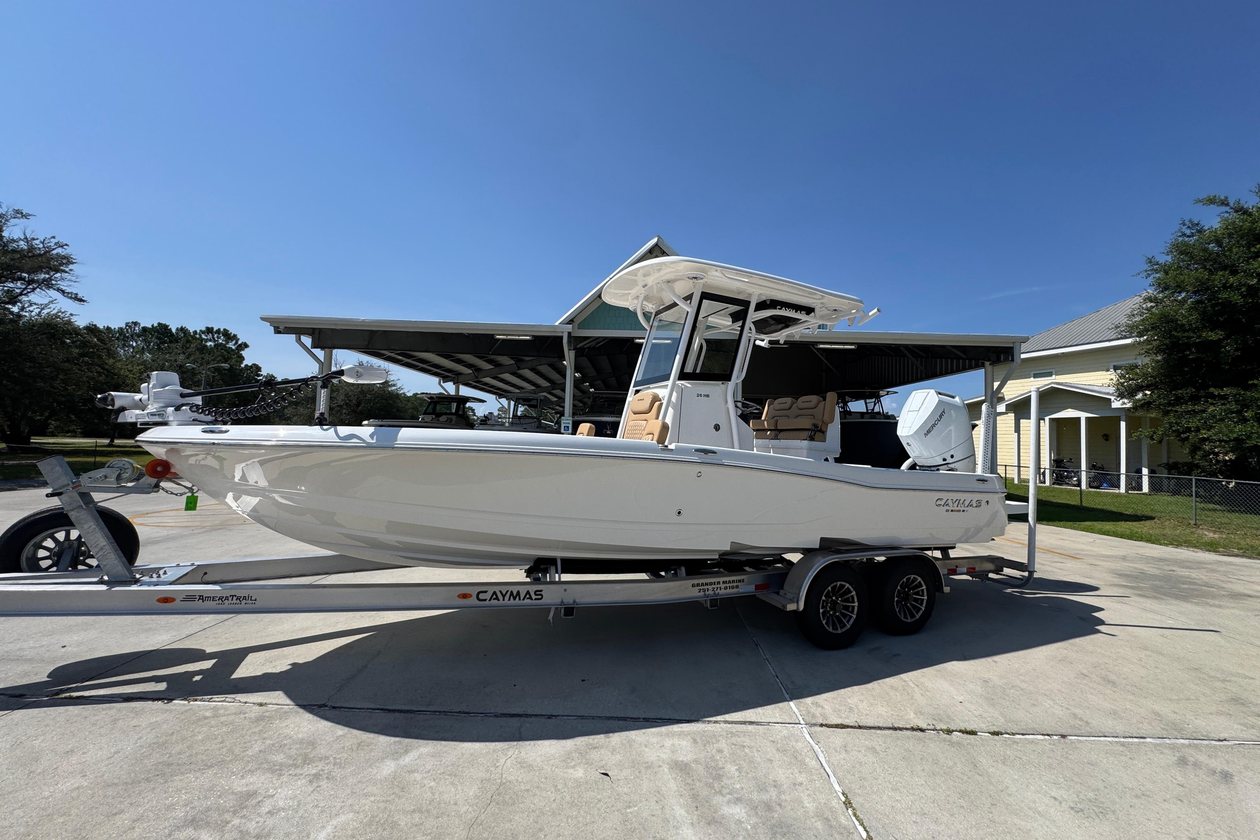 2027 Caymas 26 HB boat on trailer, parked outdoors under clear blue sky.