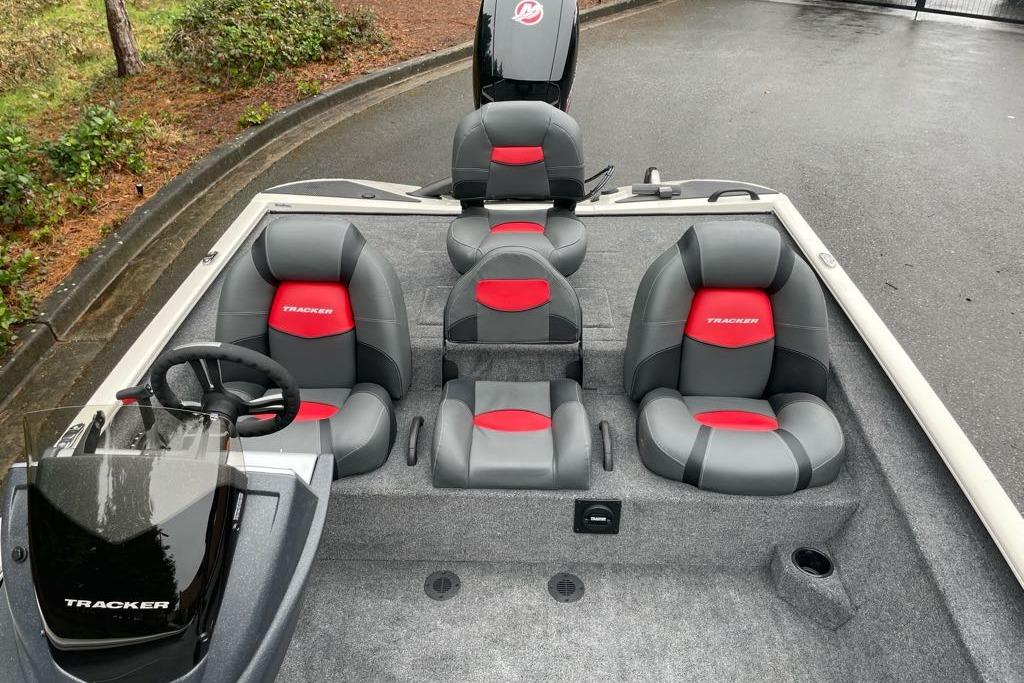 2025 Tracker Savage 215 boat interior with gray and red seating, steering wheel, and carpeted floor.