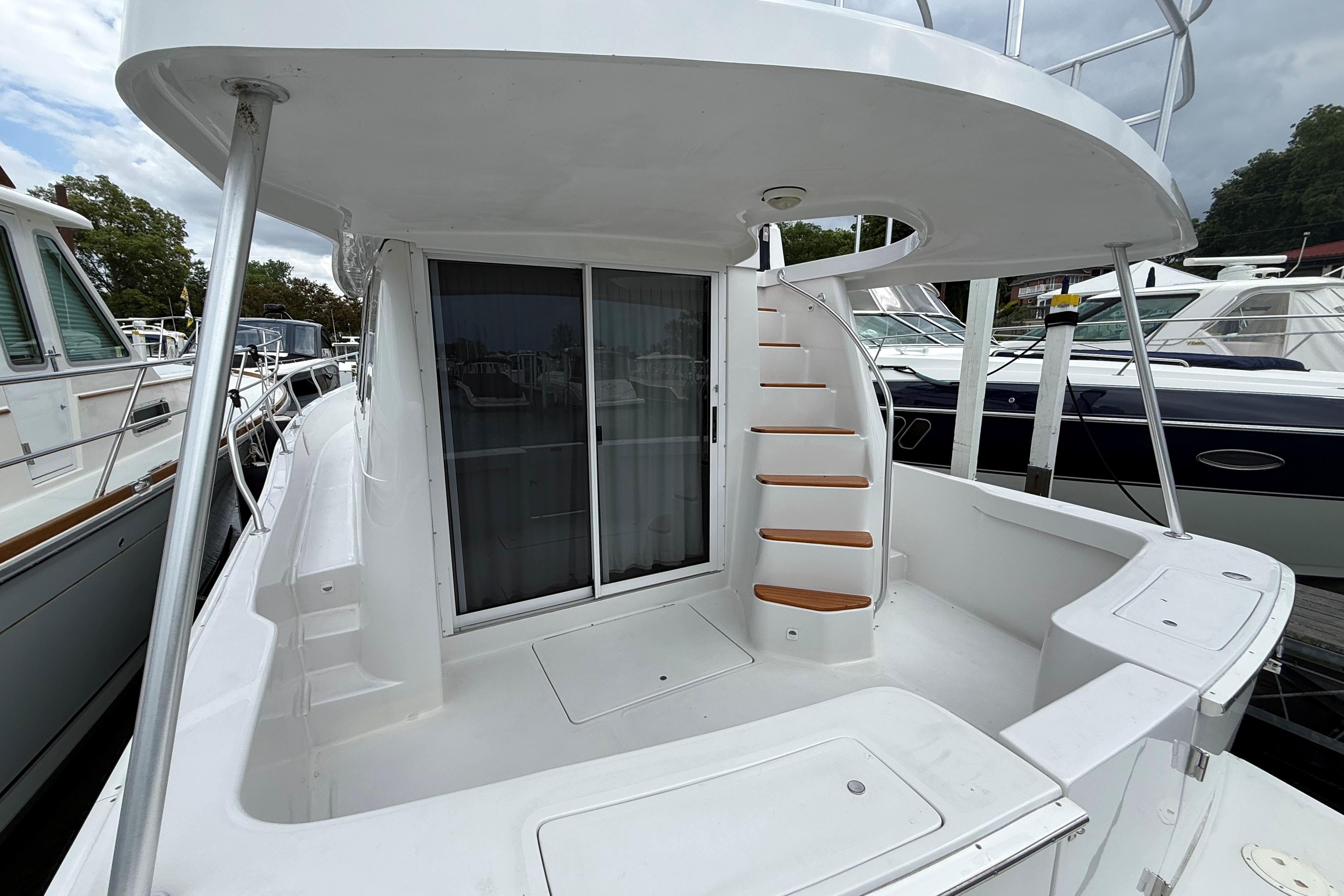 1999 Mainship 350 Trawler with spiral staircase and sliding glass doors, docked at marina.