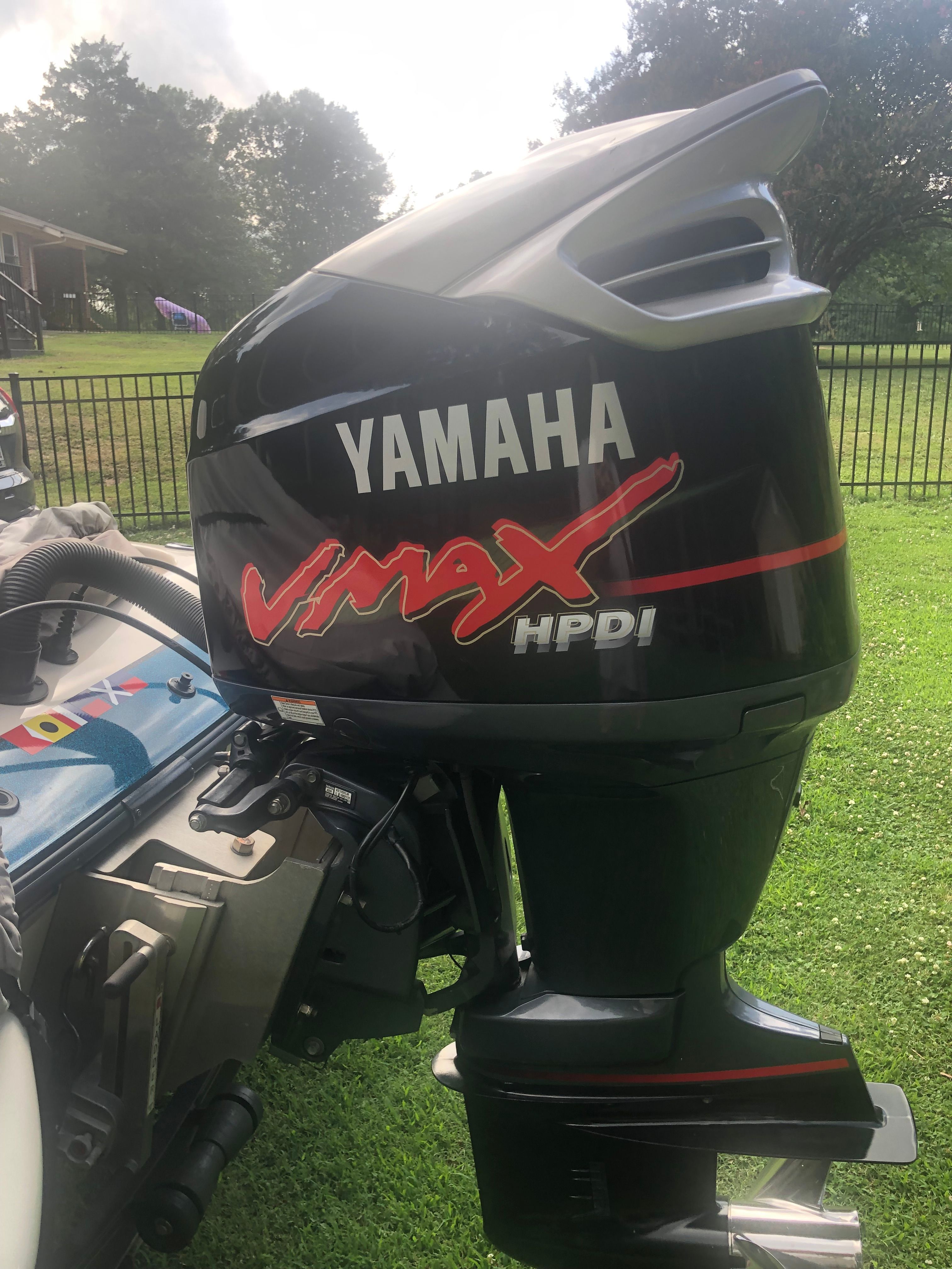 A Yamaha Vmax HPDI outboard motor is attached to a boat, which is on a lawn.