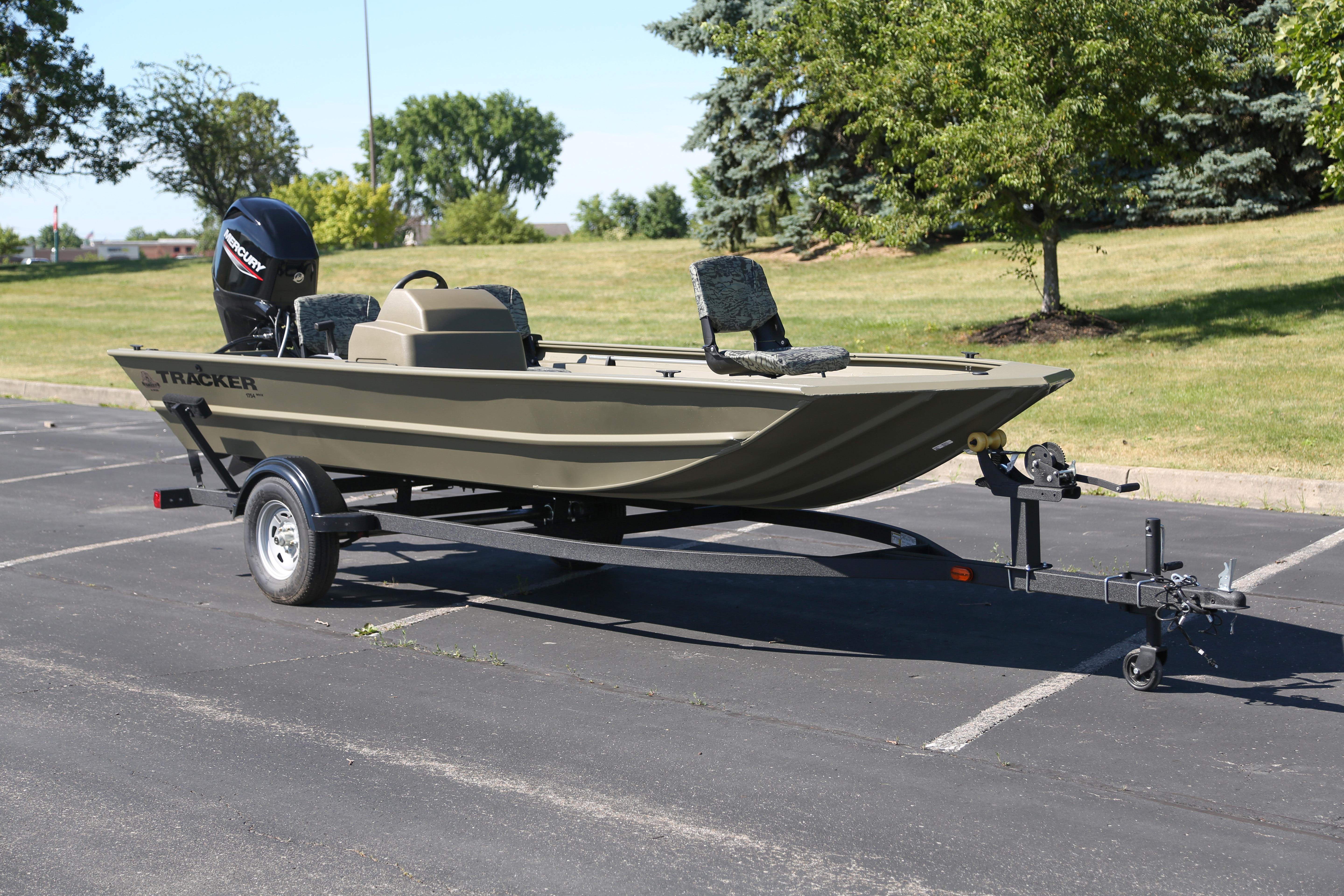 2026 Tracker Grizzly 1754 SC boat on trailer in parking lot, surrounded by greenery.