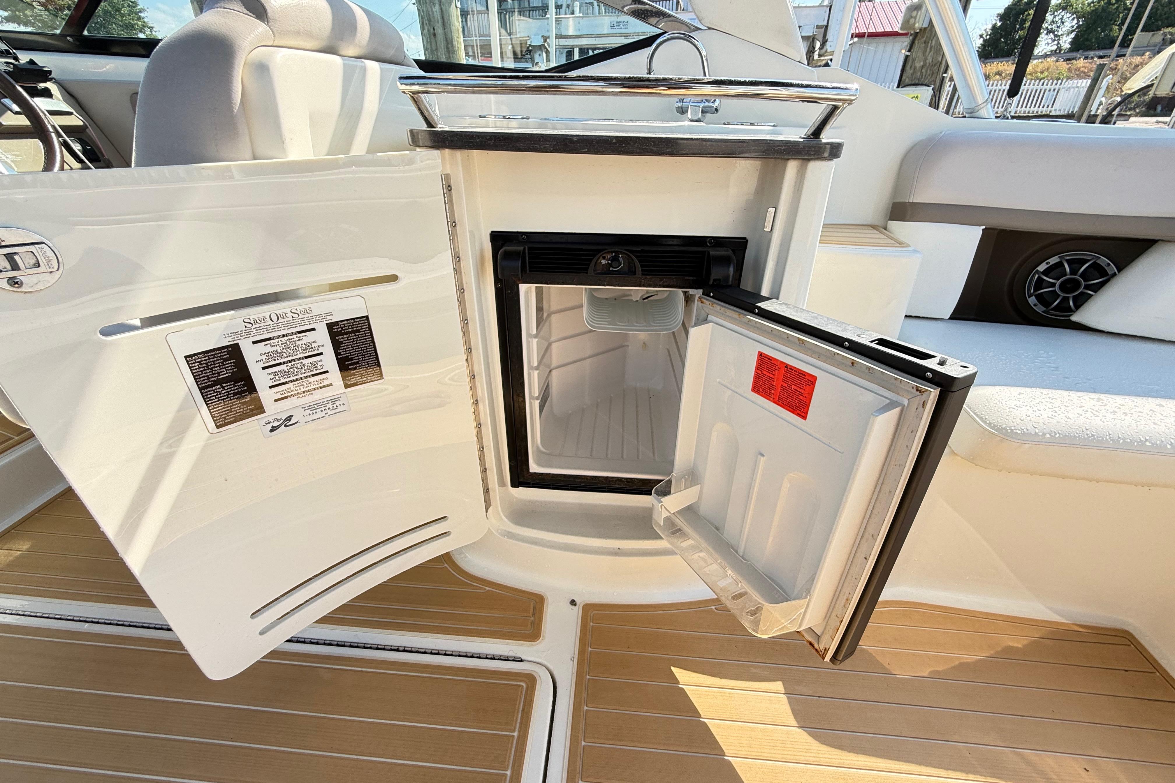 Open mini fridge on 2011 Sea Ray 270 SLX boat, showcasing interior and seating area.