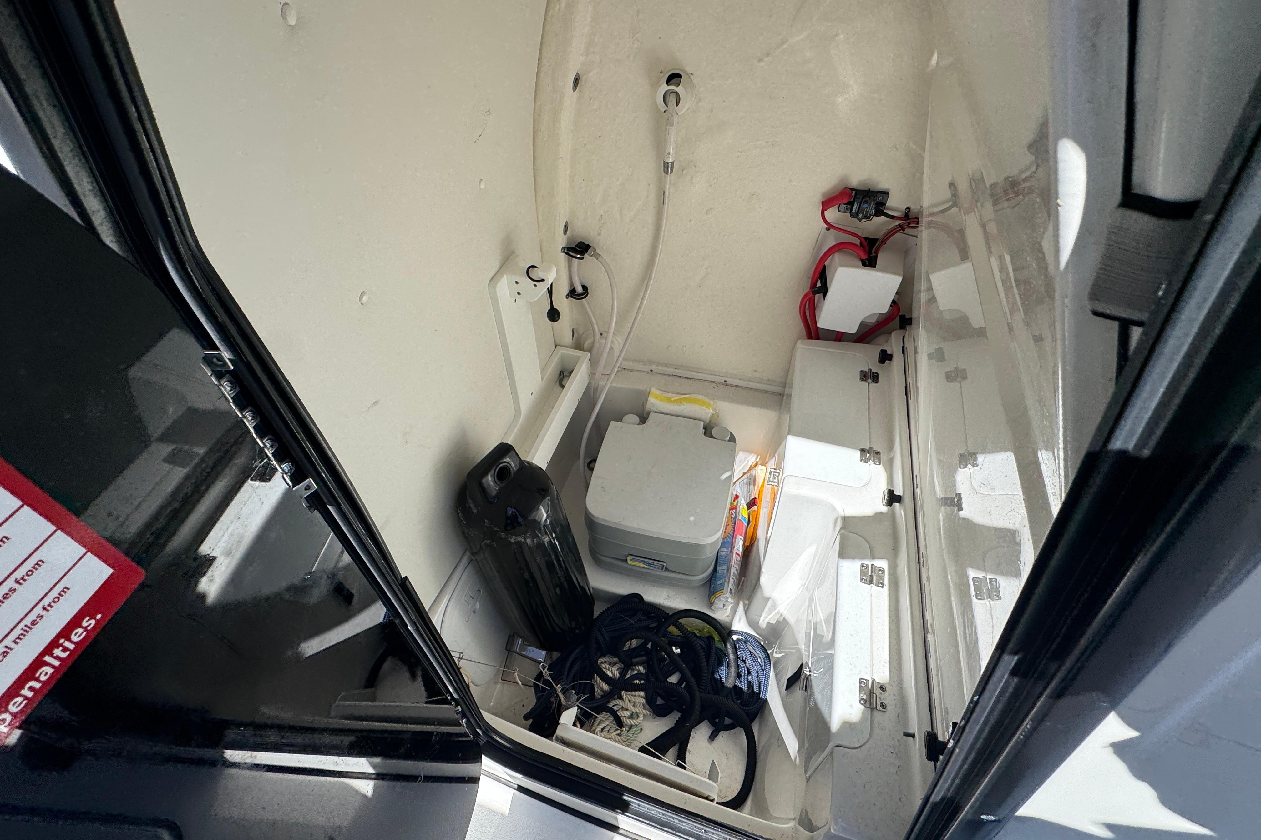 Interior storage compartment of 2022 Tidewater 256 CC Adventure boat, featuring various equipment.