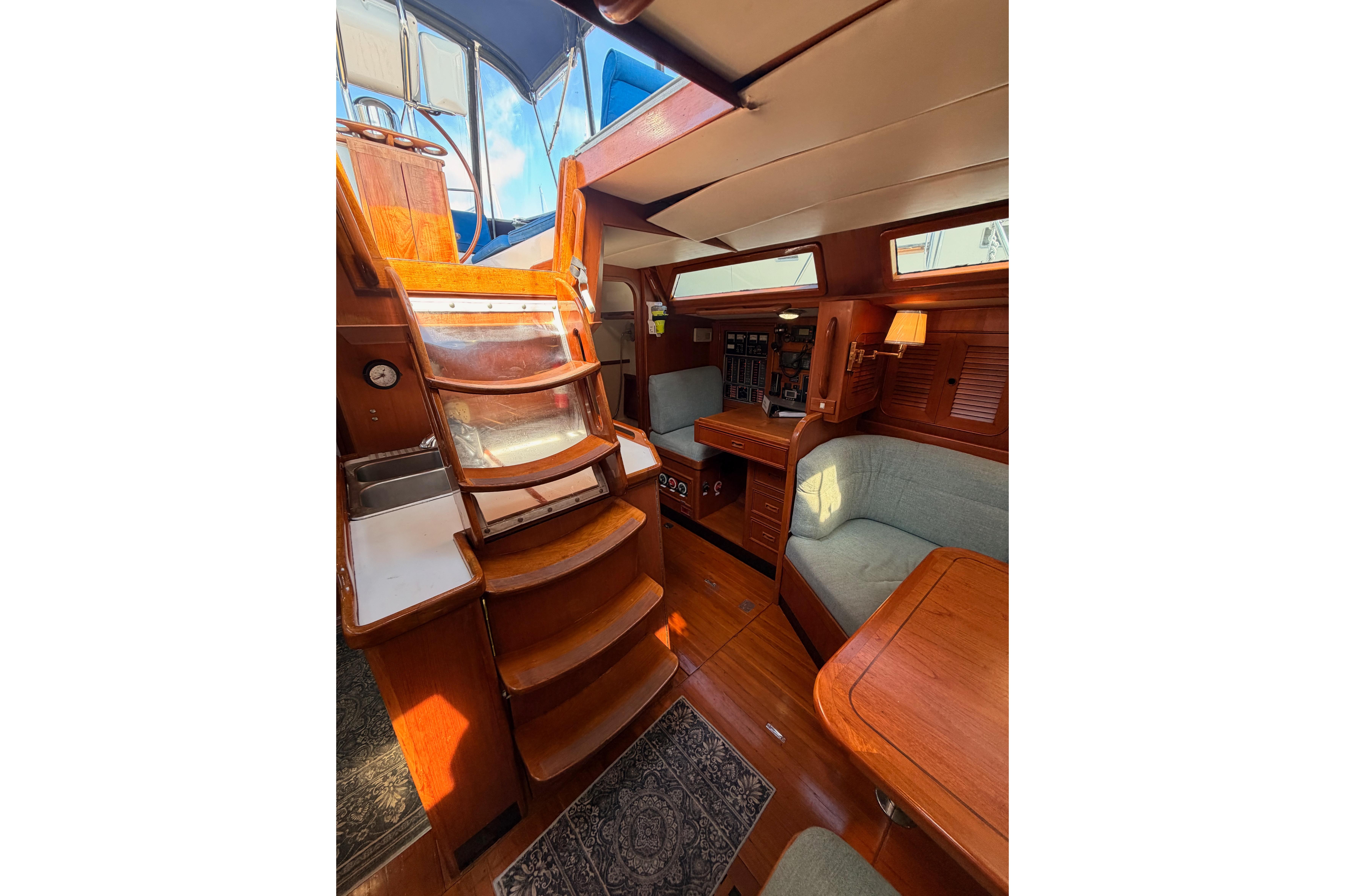 Interior of a 1991 Hylas 51 yacht featuring wooden stairs and cozy seating area.