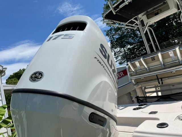 An outboard motor on a Carolina Skiff 21 Ultra Elite boat, surrounded by trees and blue sky.