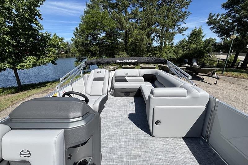 2026 Sun Tracker Party Barge 20 DLX pontoon boat with spacious seating by a serene lake.
