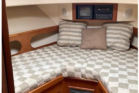 Cozy cabin interior of 2000 Mainship 430 Trawler with striped bedding and pillows.