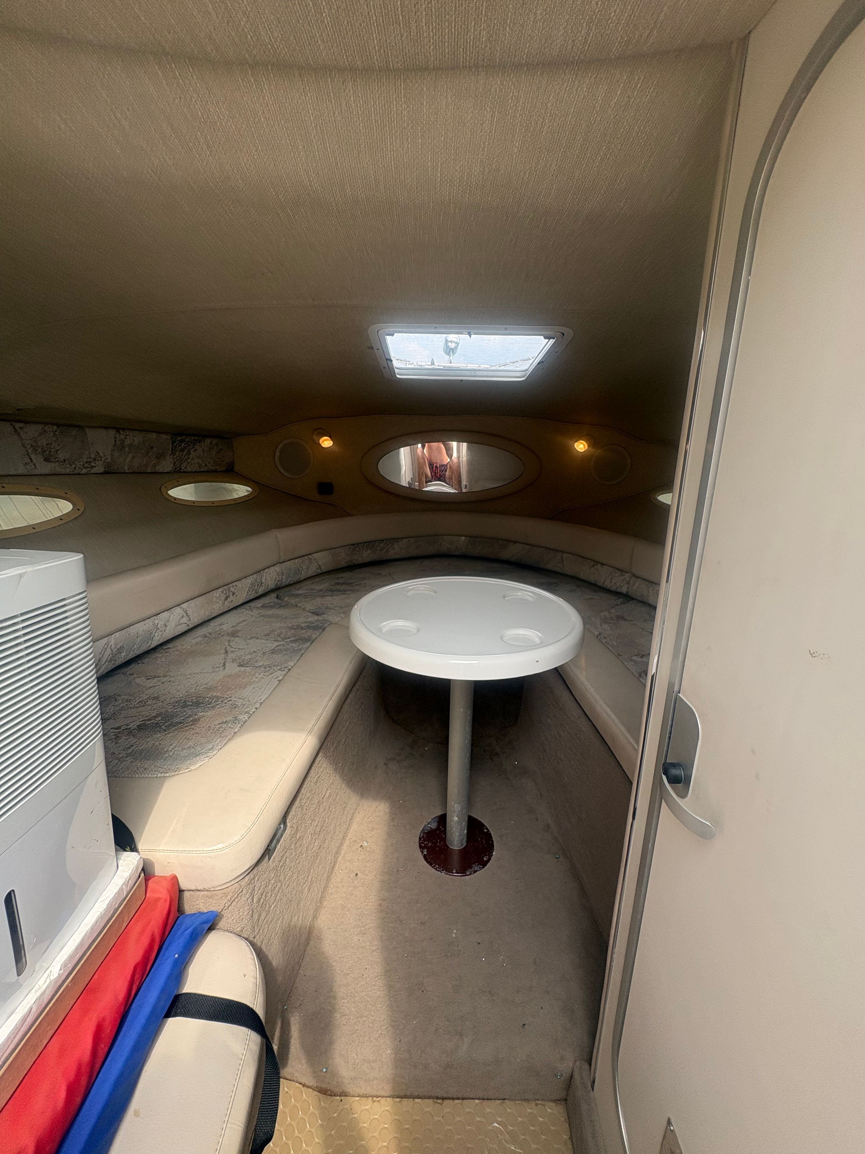 Interior of a 1996 Sea Ray 280 Cuddy Cabin with seating area and table.