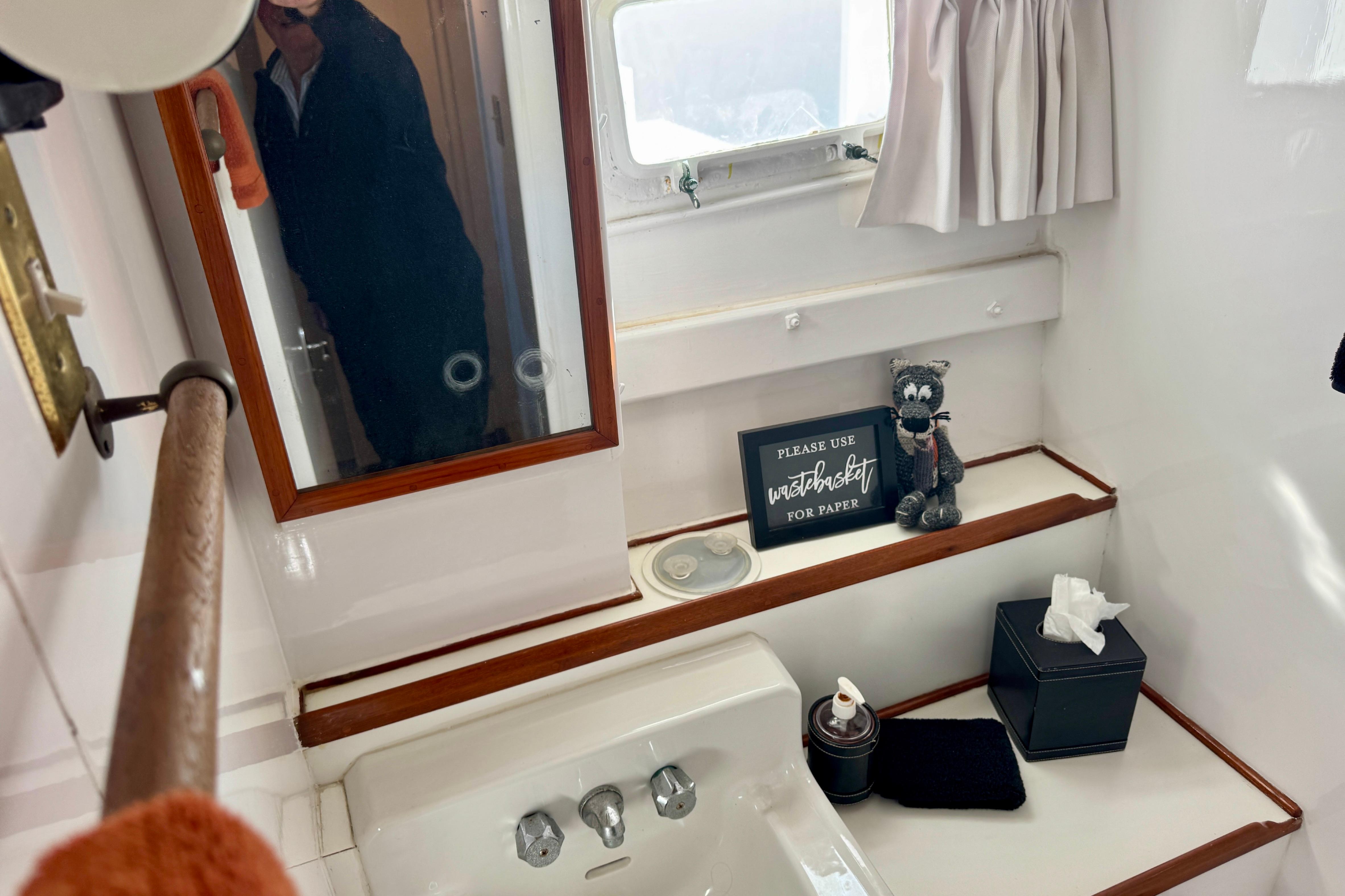 1958 Blanchard Pilothouse bathroom with mirror, sink, and decorative items.