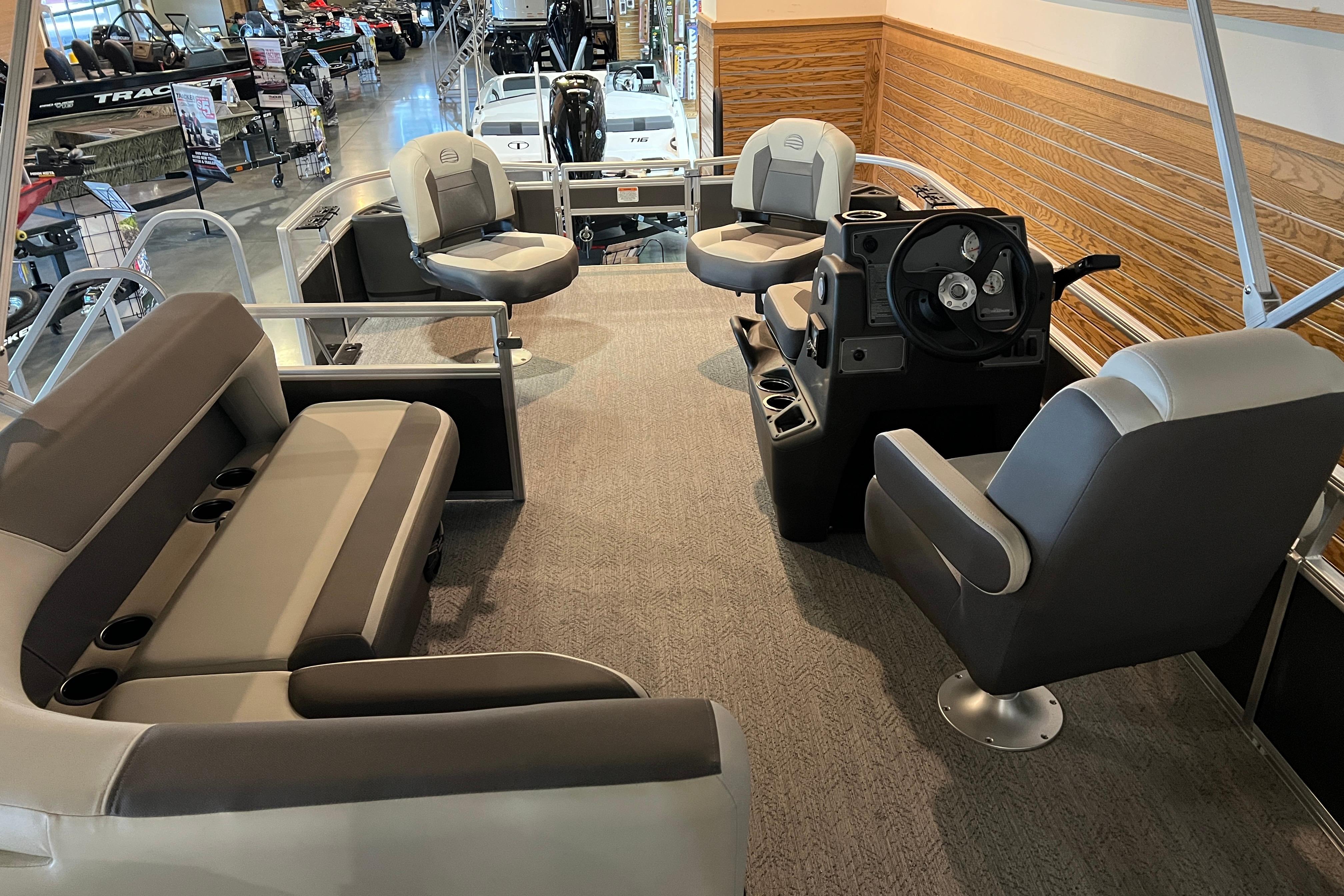 2026 Sun Tracker Bass Buggy 18 DLX interior with seating and steering console in showroom.