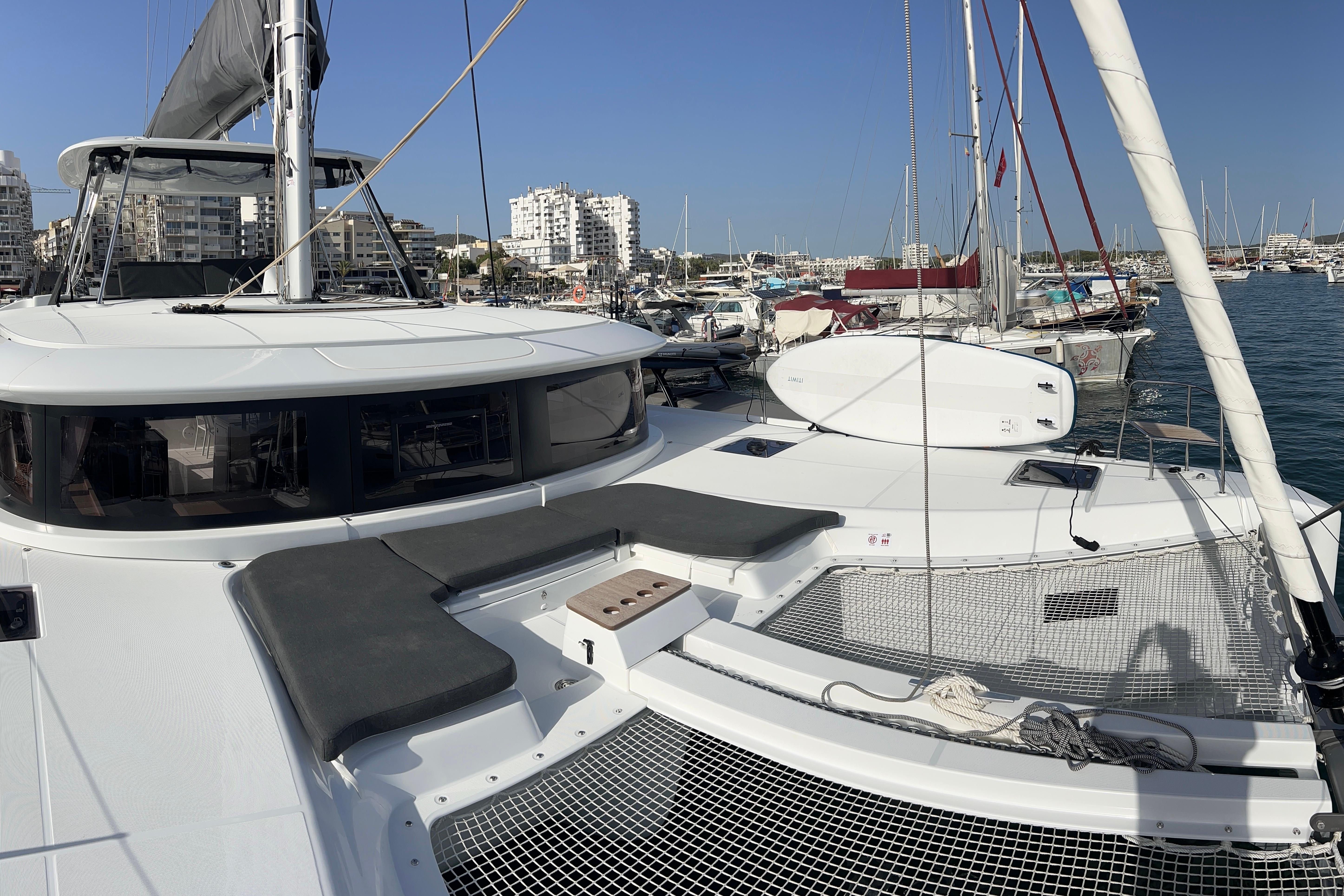 2024 Lagoon 46 catamaran docked in a marina, showcasing spacious deck and modern design.