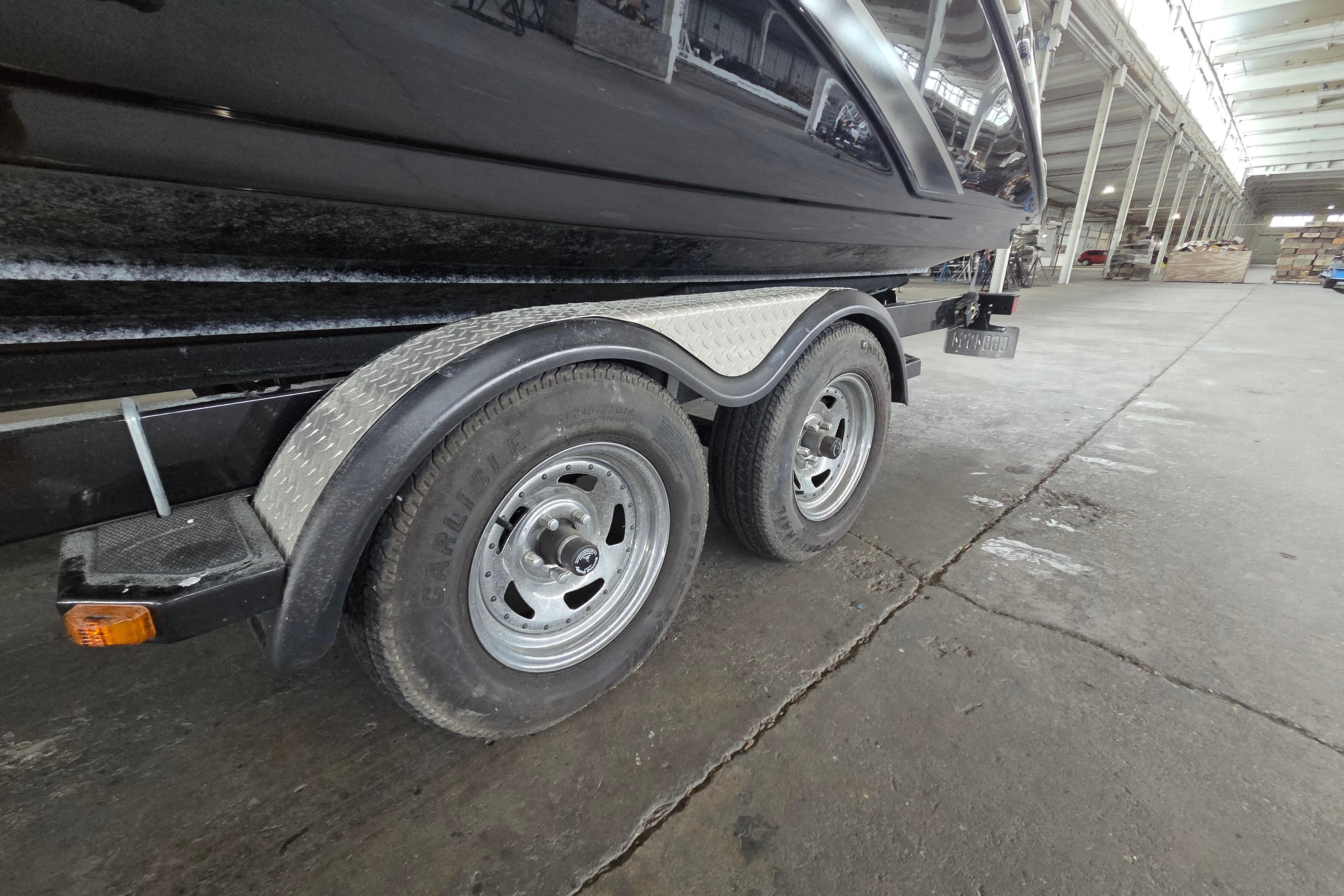 Trailer of a 2013 Yamaha 242 Limited S boat in a warehouse setting.