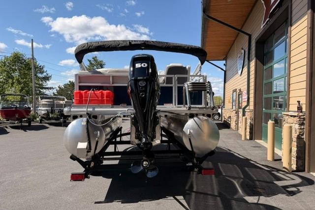 2026 Sun Tracker Bass Buggy 16 XL Select pontoon boat with 50 HP engine, parked outdoors.
