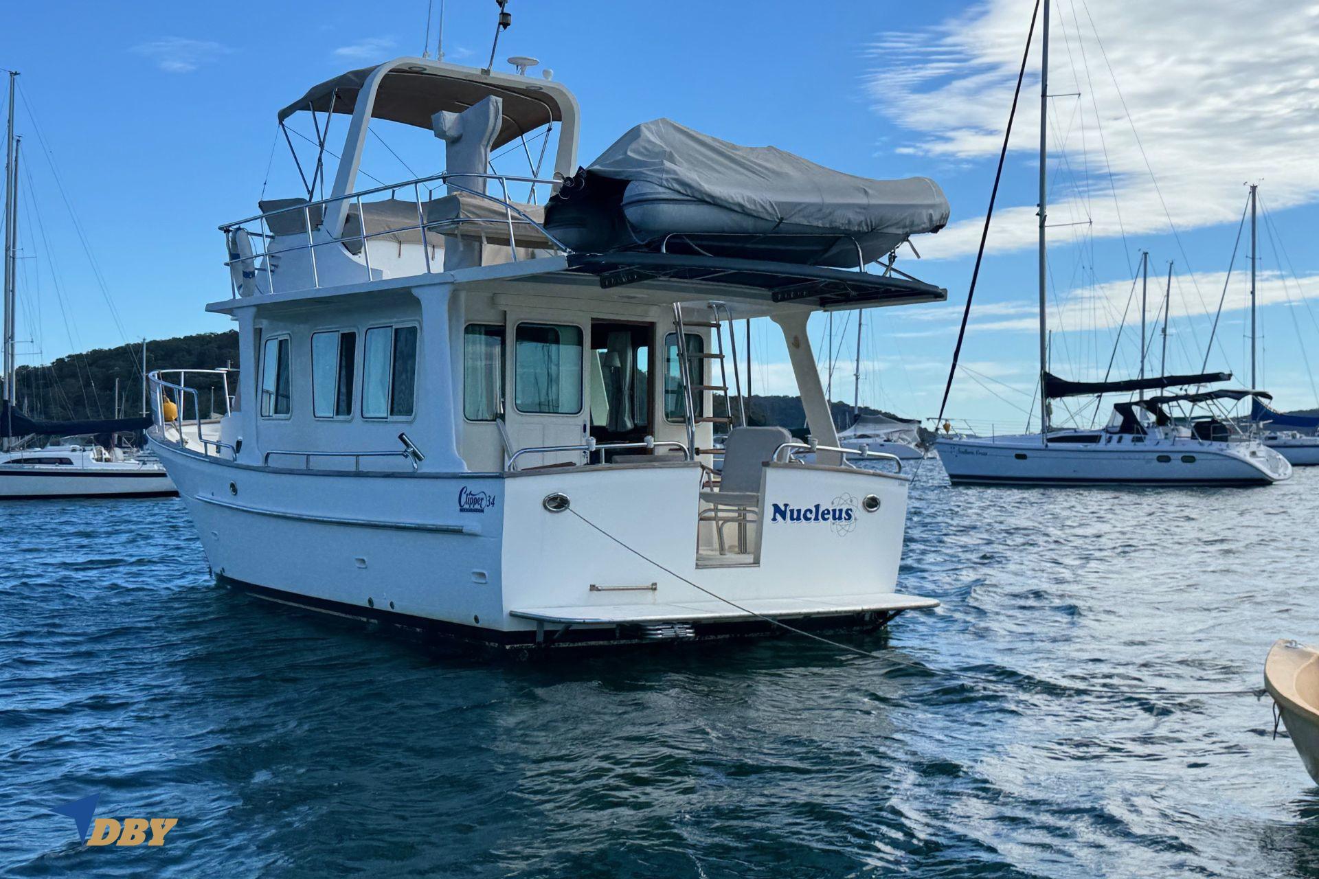 Clipper 34 boat from 2006 named "Nucleus" docked in a marina with sailboats.