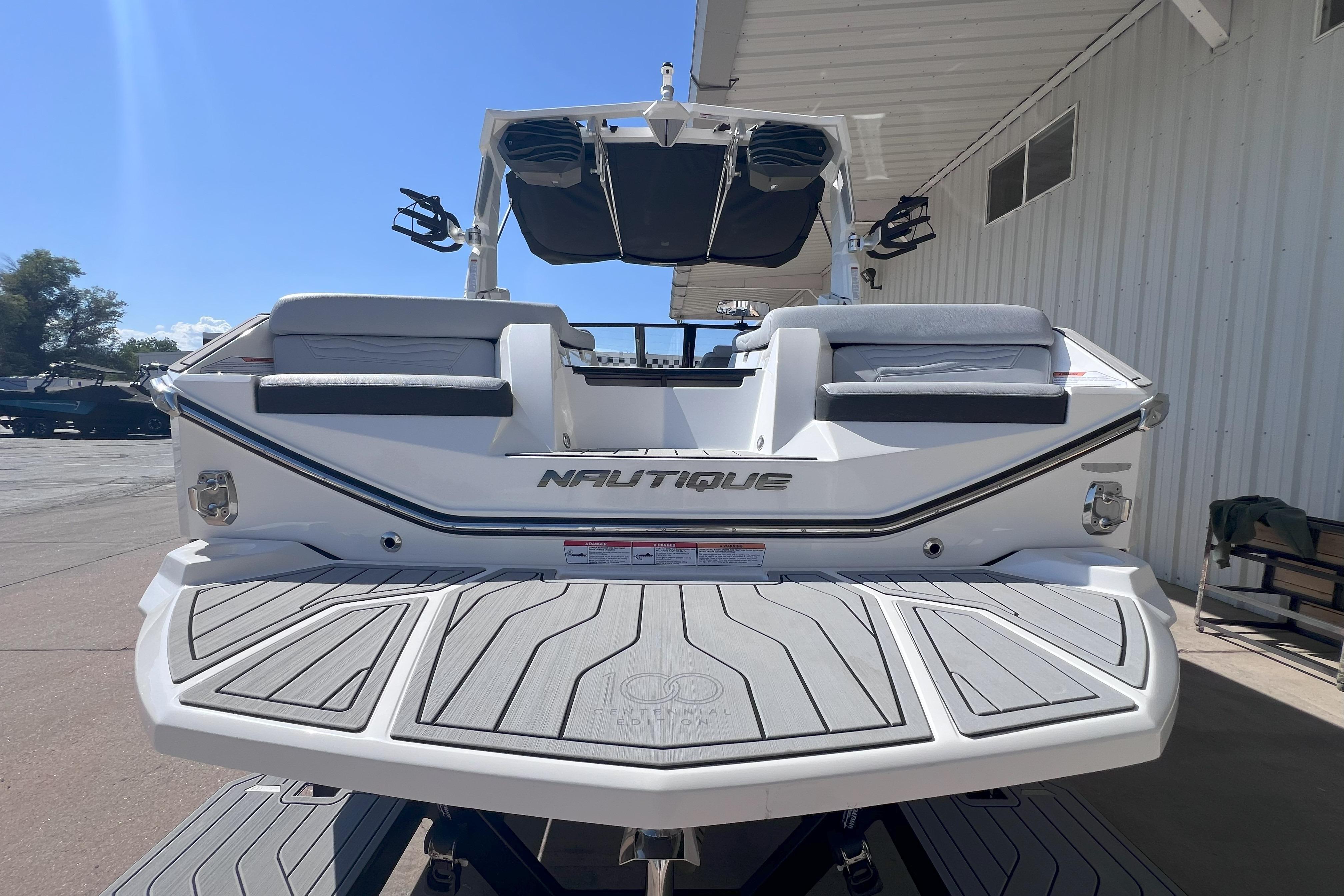 2025 Nautique Super Air Nautique G21 boat, rear view, docked under a canopy.