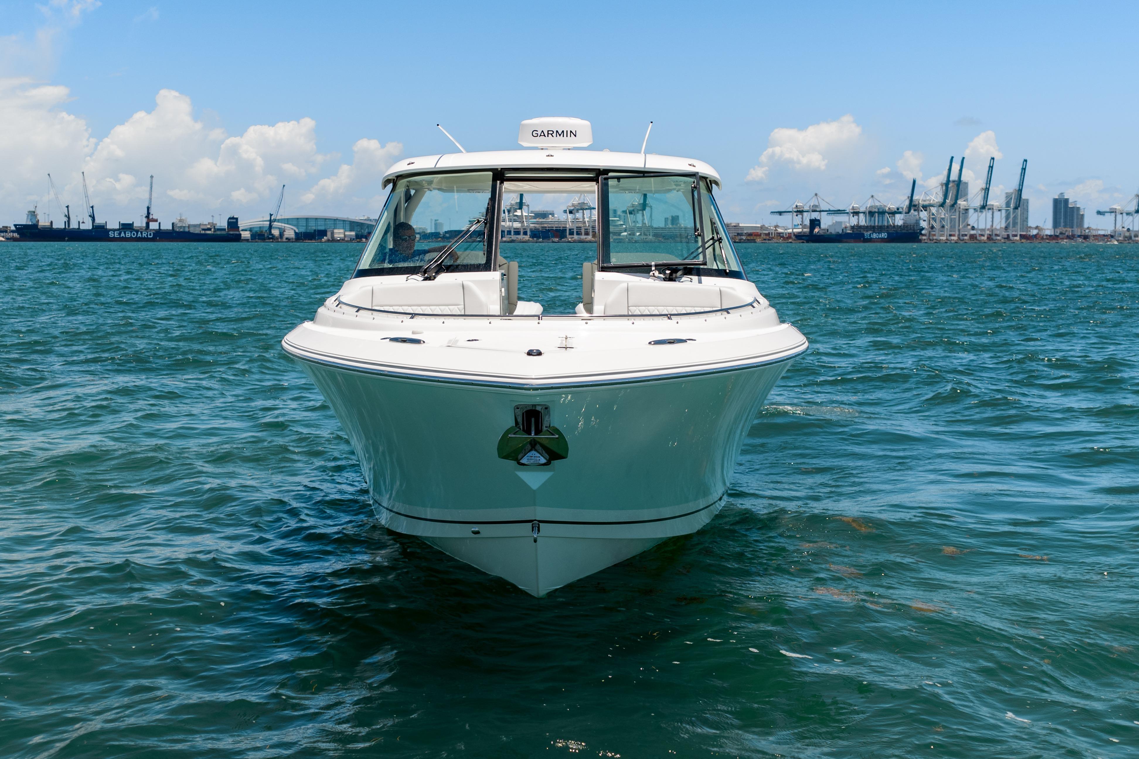 2026 Pursuit DC 326 Dual Console boat on water, with industrial port background.