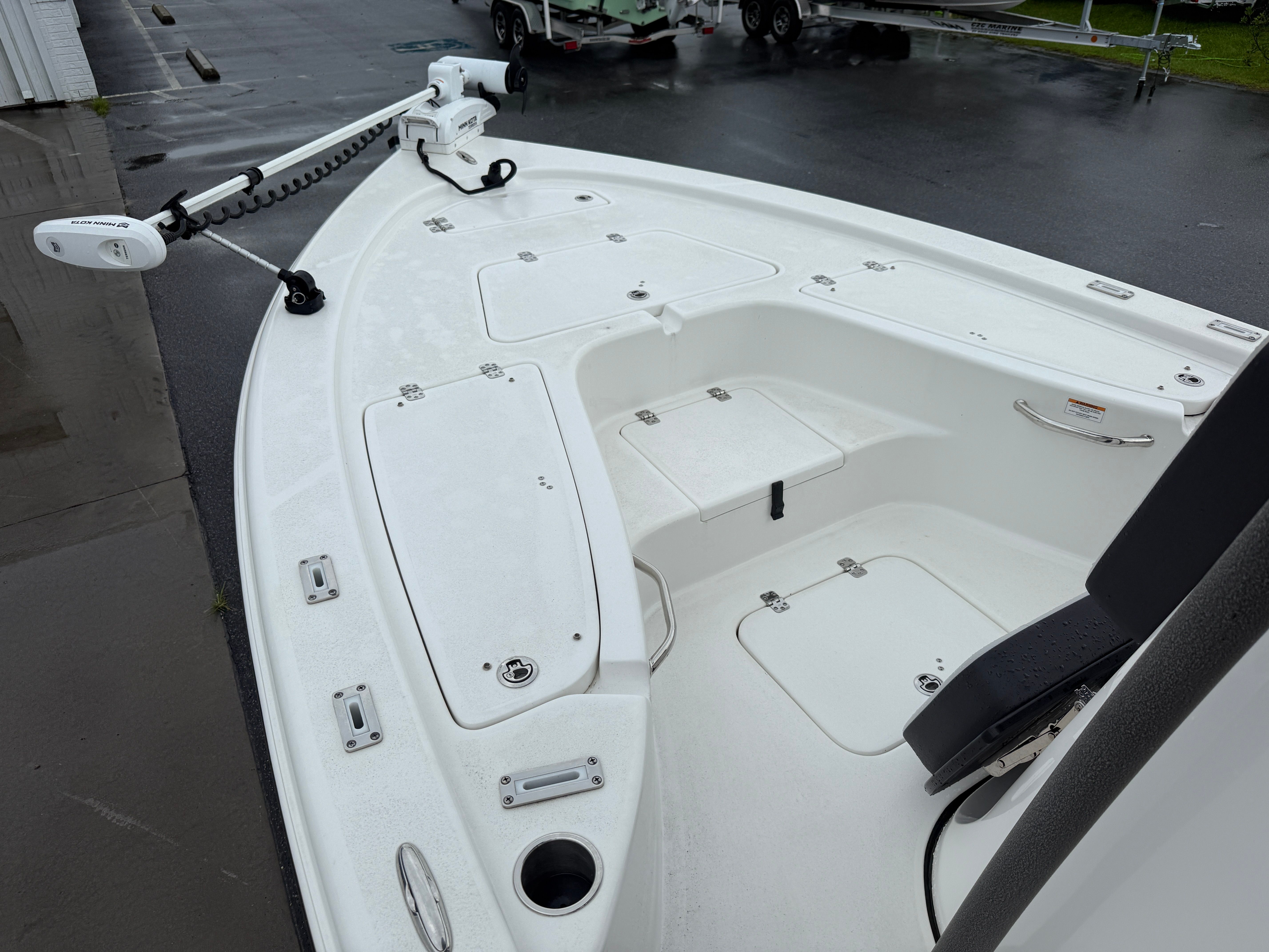 The image shows the deck of a 2025 Sea Pro 230 DLX boat with storage and fishing rod holders.