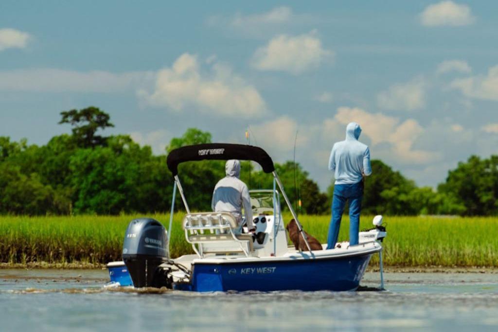 2026 Key West 1720 Center Console boat on a serene river with two people fishing.