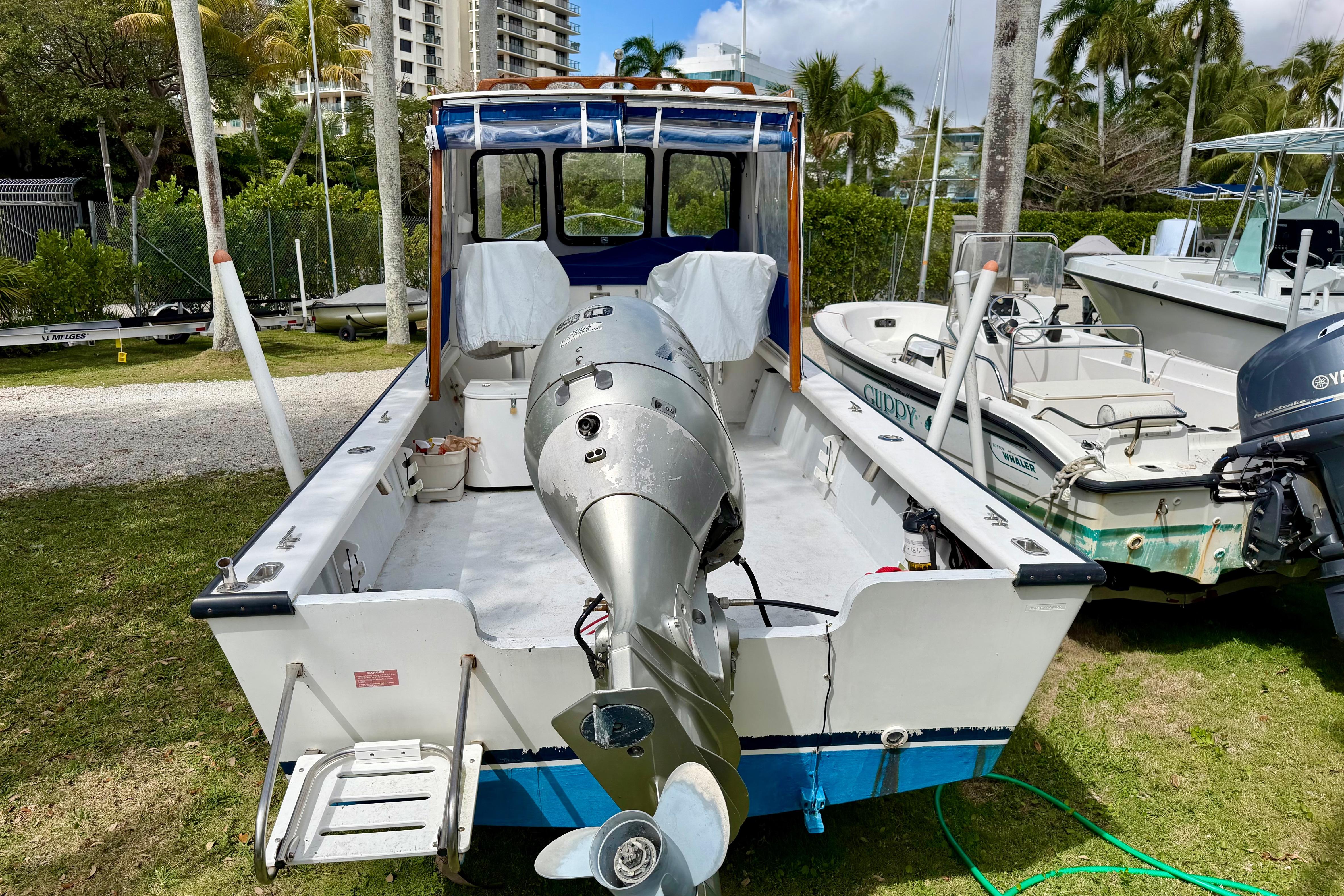 2000 Eastern 22 Lobster Fisherman boat with outboard motor, parked on grass near other boats.