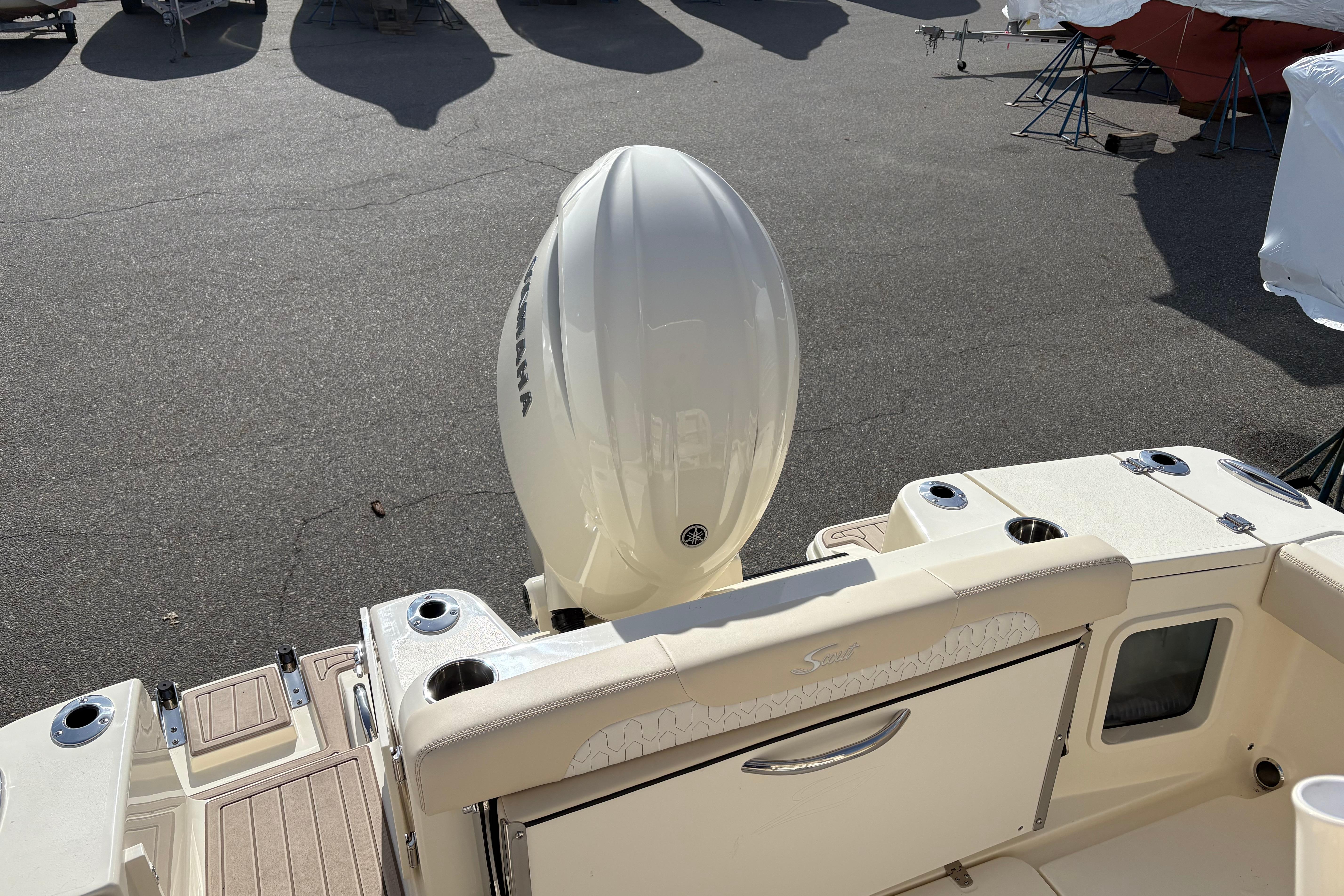 2026 Scout 220 XSF boat with outboard motor in a parking area.