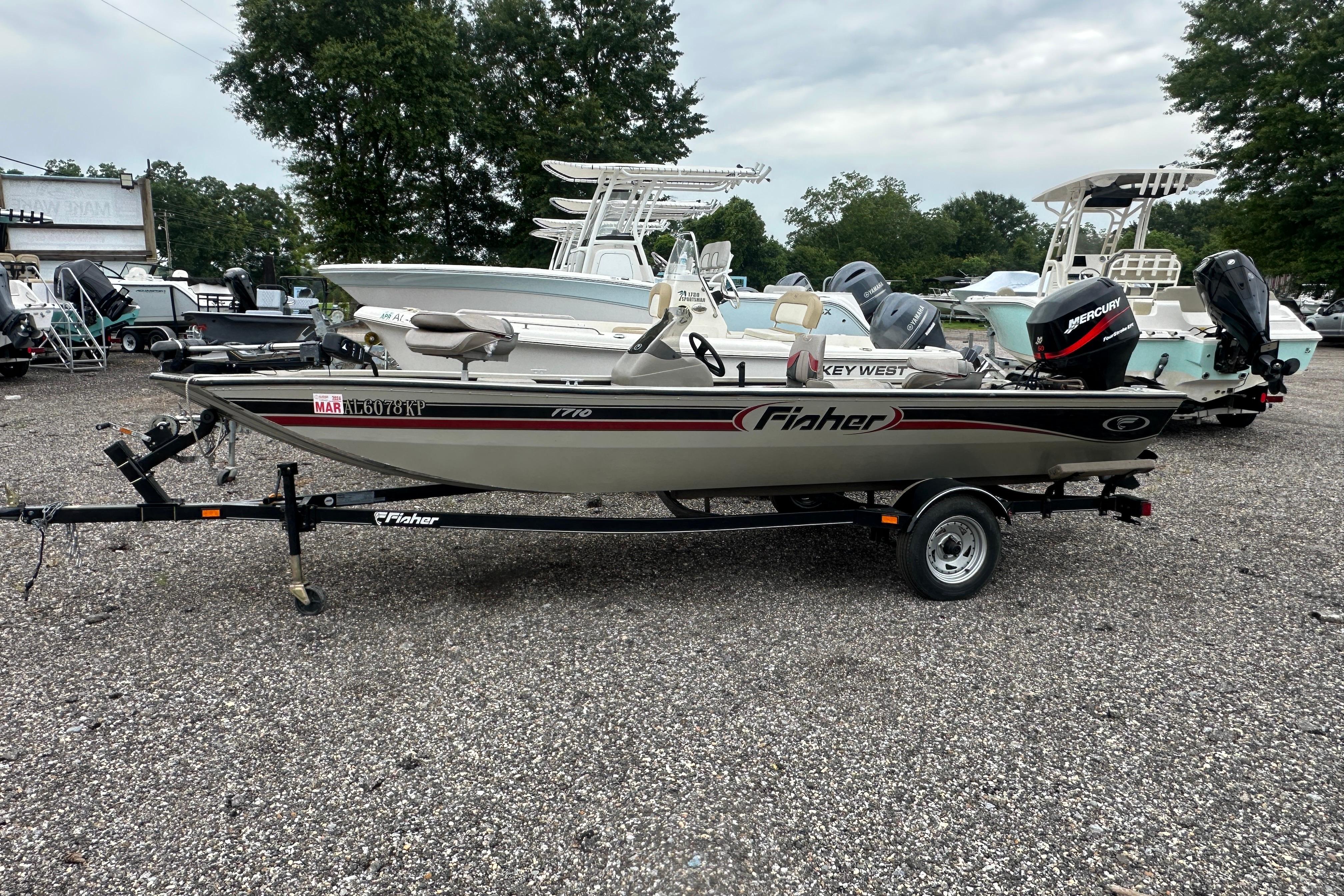 2002 Fisher 1710 boat on trailer, parked in a gravel lot with other boats.