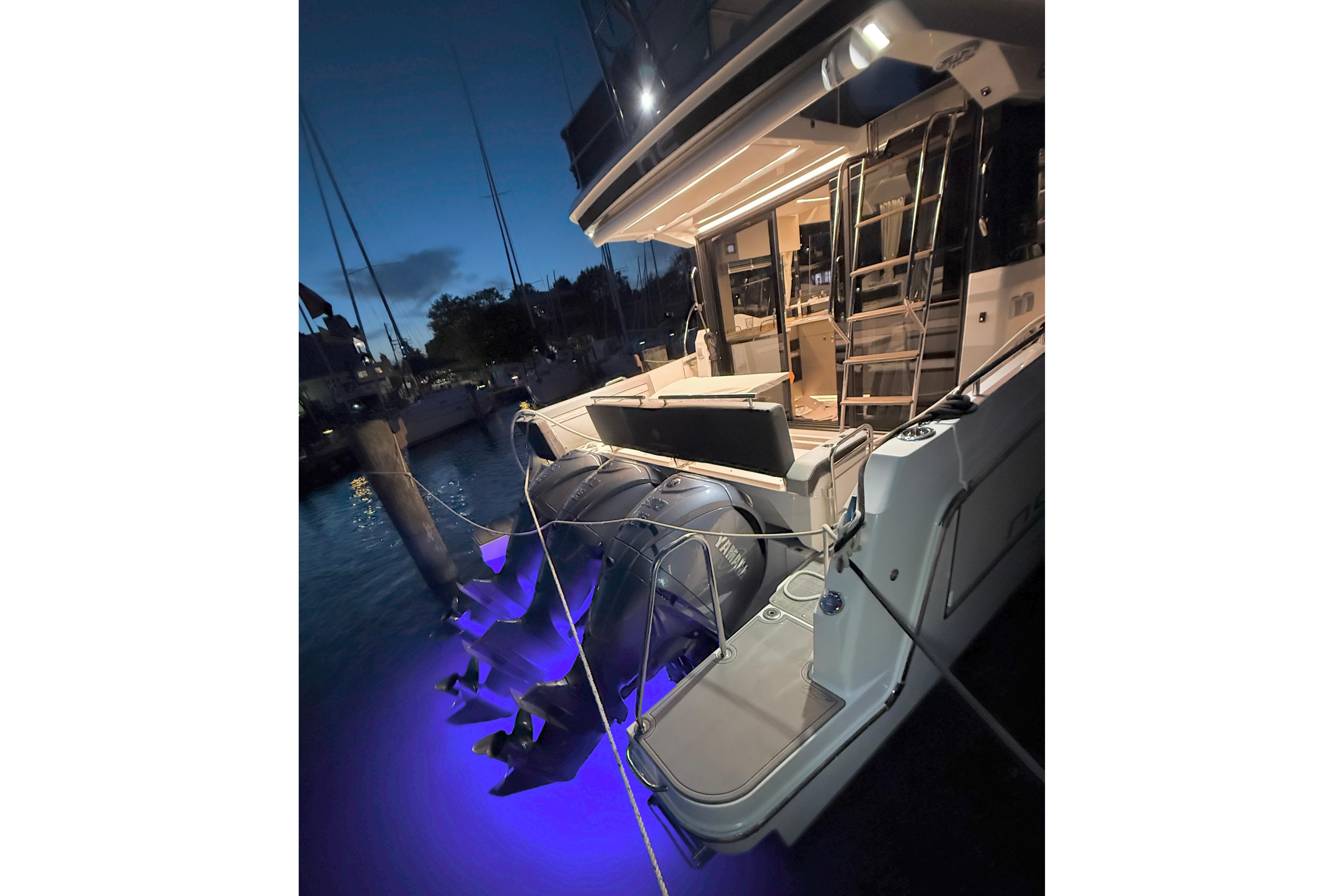 2024 Jeanneau NC Weekender 1295 Fly yacht docked at night with illuminated water.