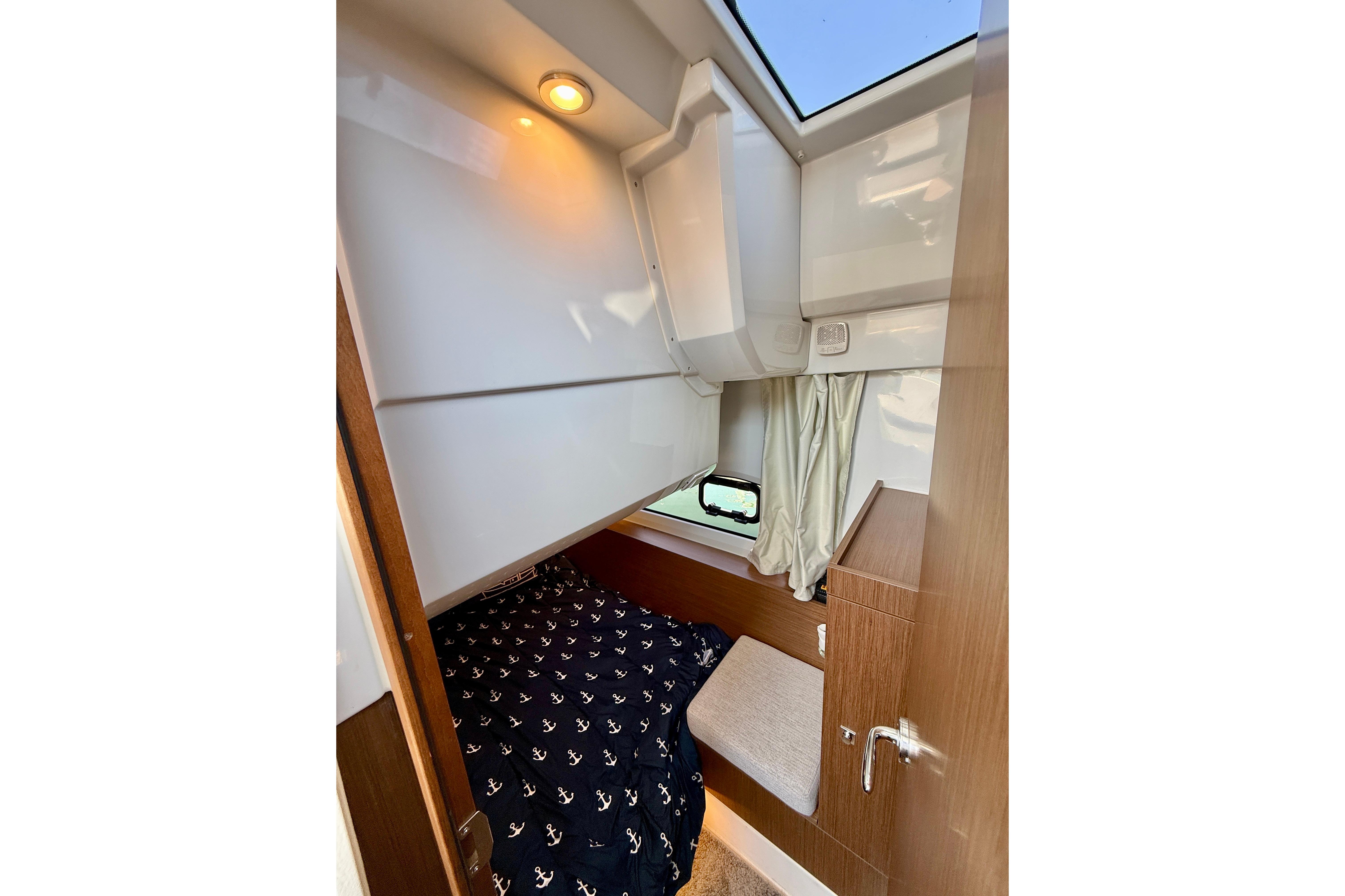 Cozy cabin interior of 2022 Jeanneau NC 1095 Fly with nautical-themed bedding.