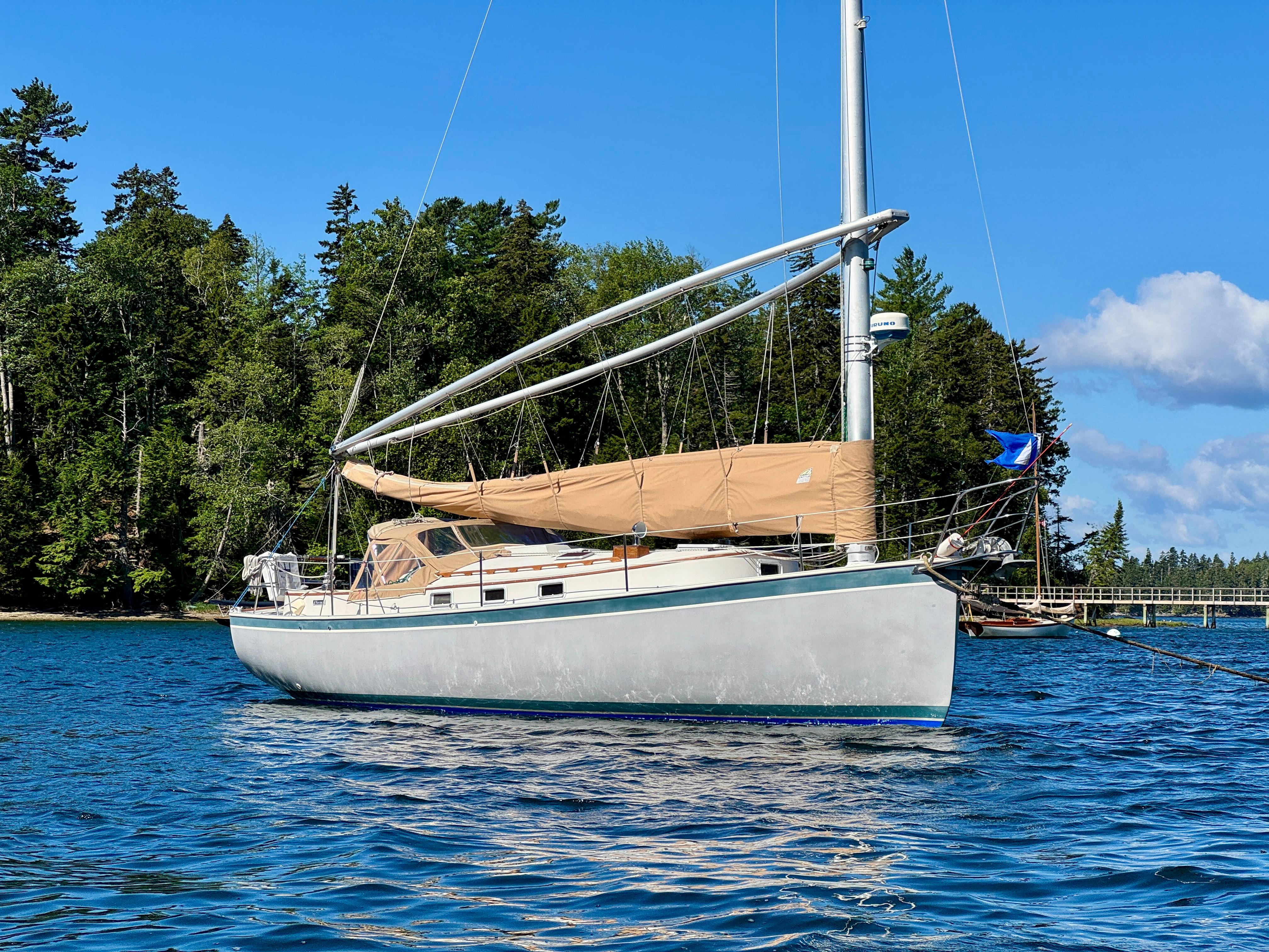Sailboat Nonsuch 30 Ultra 1989 anchored in scenic waters with forested background.