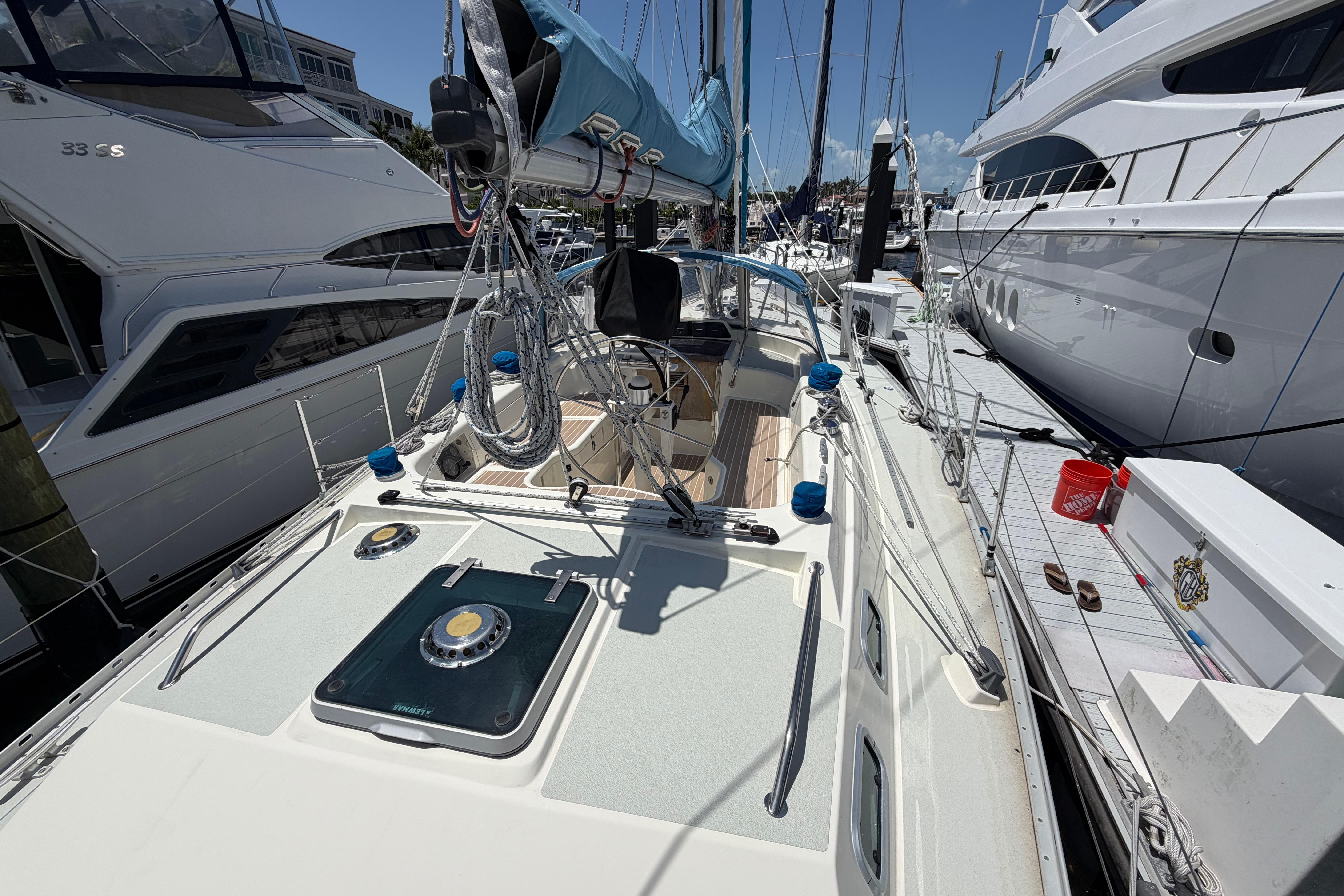 1987 Moody 376 sailboat docked among luxury yachts on a sunny day.