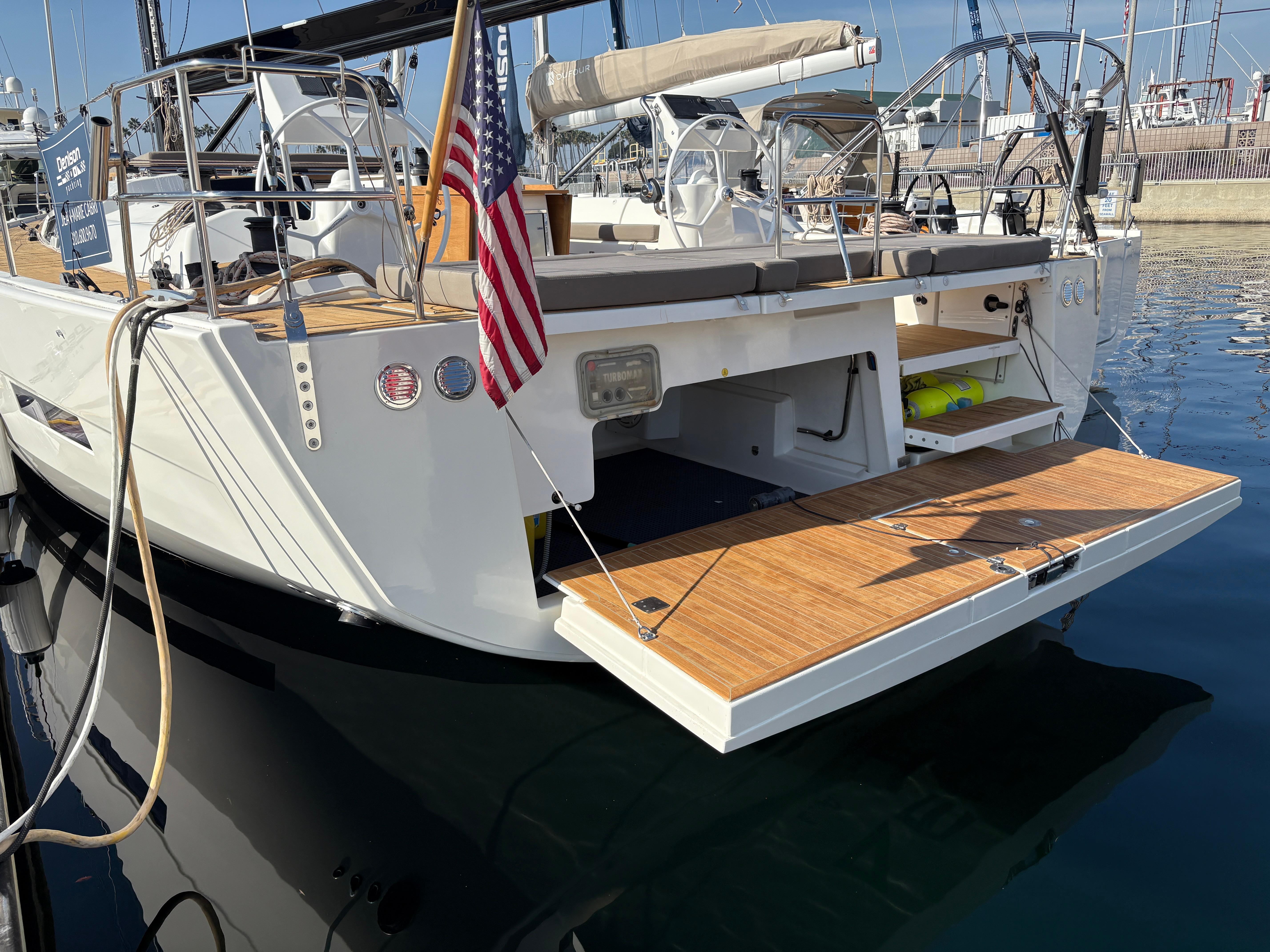 Dufour 560 Exclusive 2018 yacht with open swim platform, docked in marina.