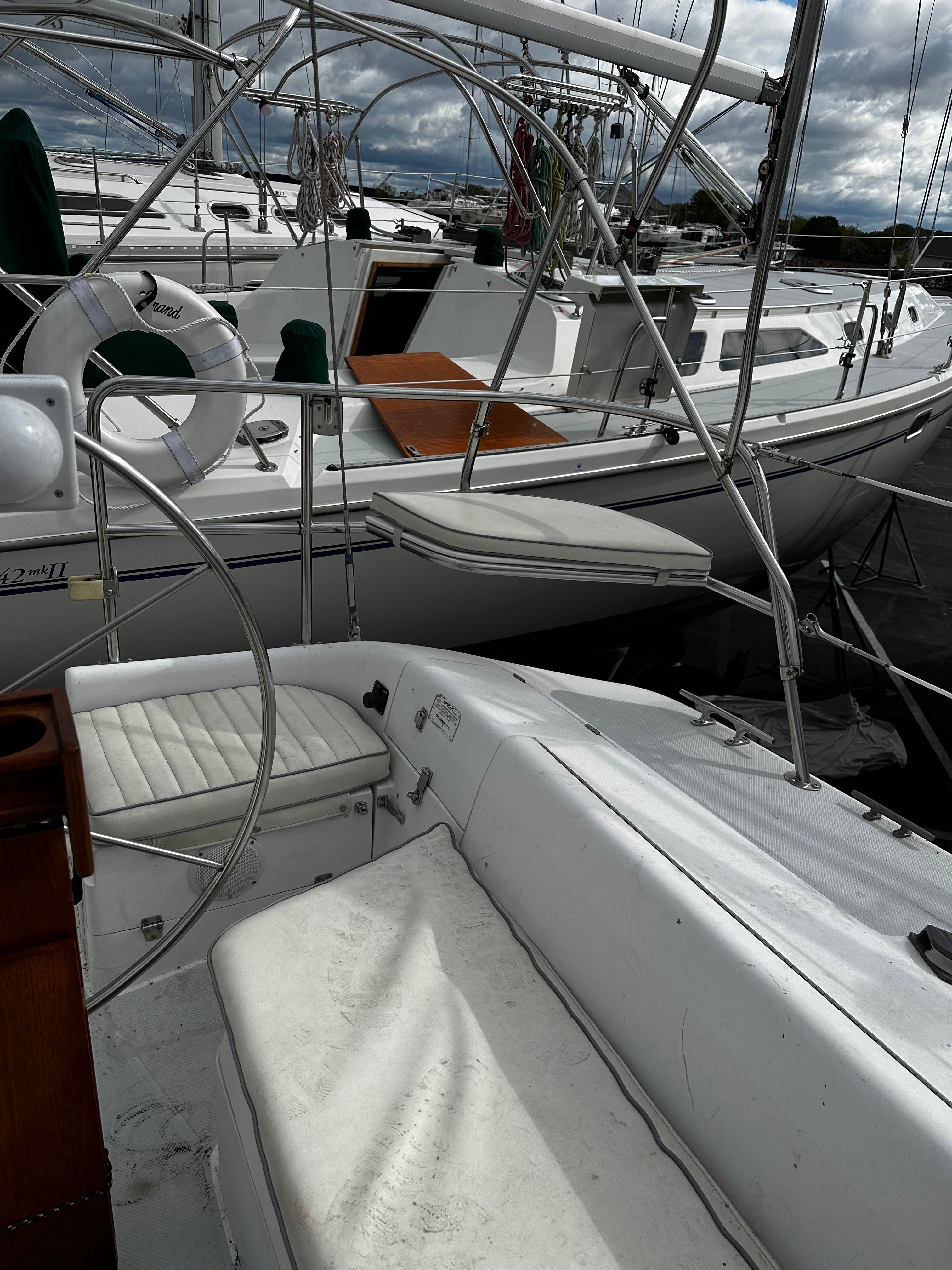 A sailboat with white seats and metal railings docked in a marina.