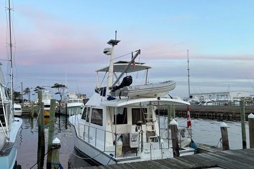 2007 Island Pilot 395 docked at marina during sunset, featuring upper deck and dinghy.