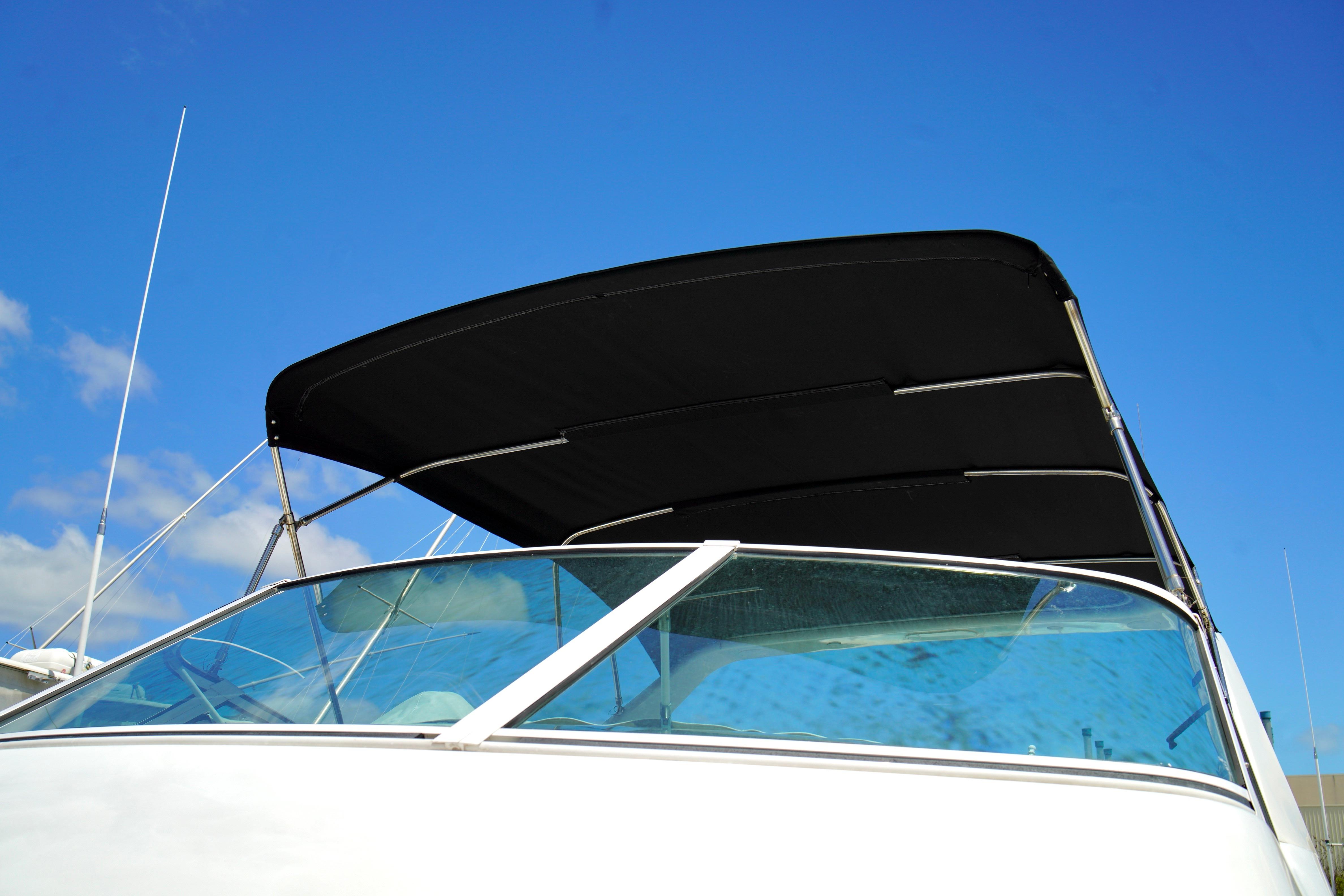 1999 Carver 450 Voyager Pilothouse boat with black canopy against blue sky.