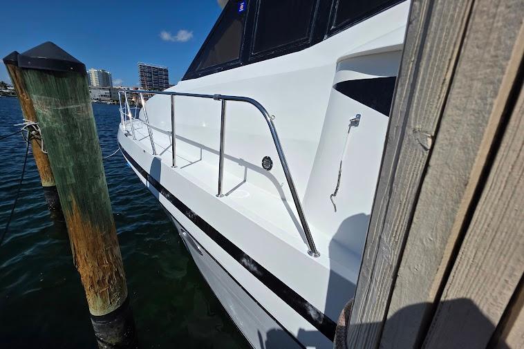 1993 McKinna 48 Pilothouse yacht docked, showcasing sleek white exterior and railing.